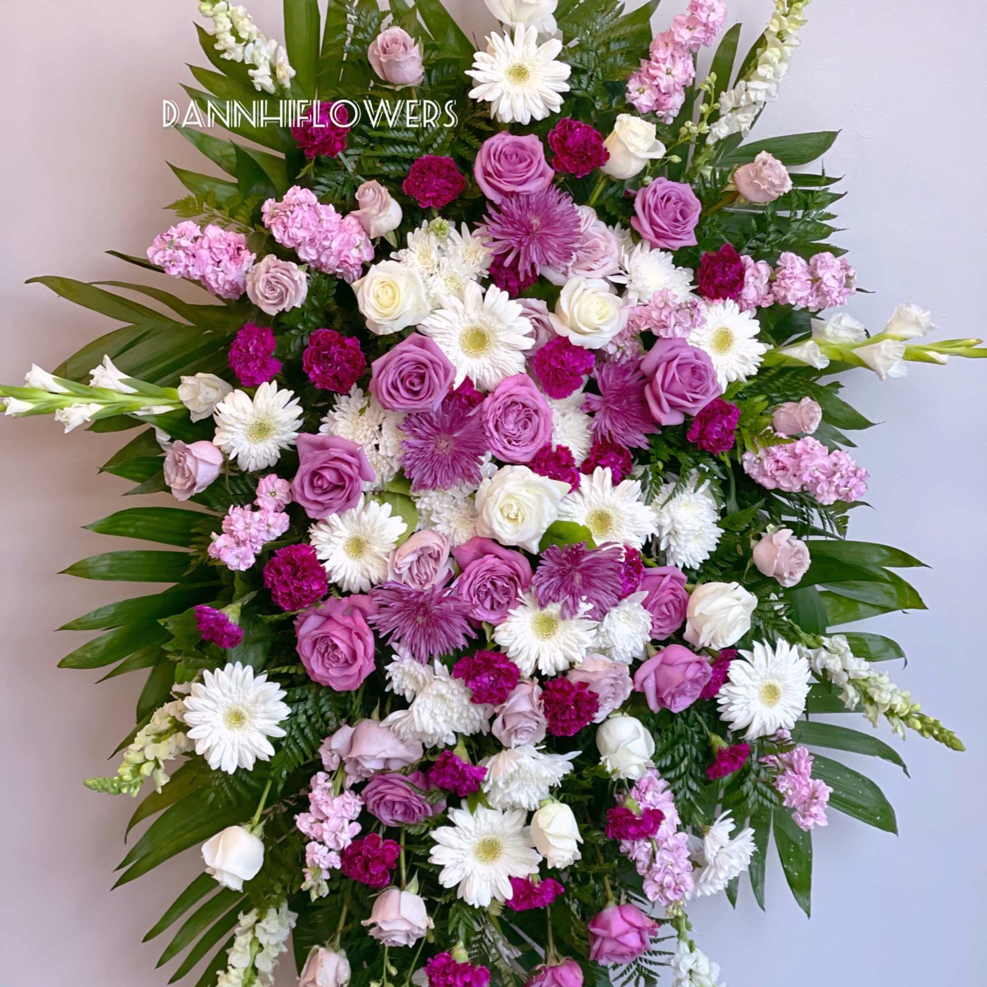 Large pink, white, and purple standing floral spray with roses and daisies