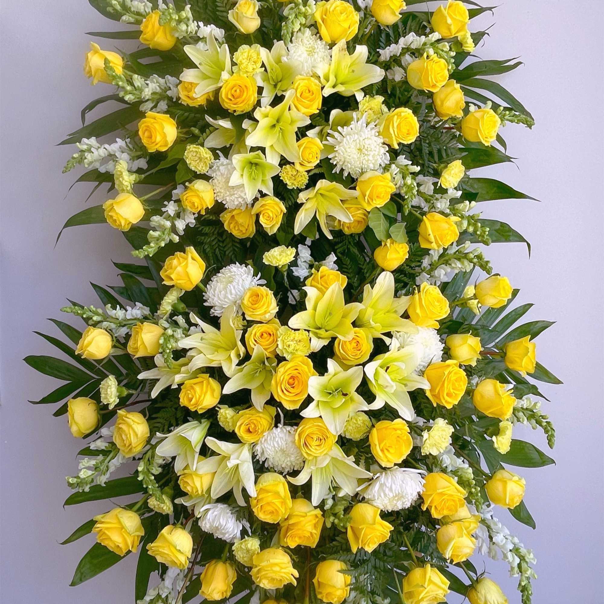 Large standing spray of yellow roses and white lilies with white accents