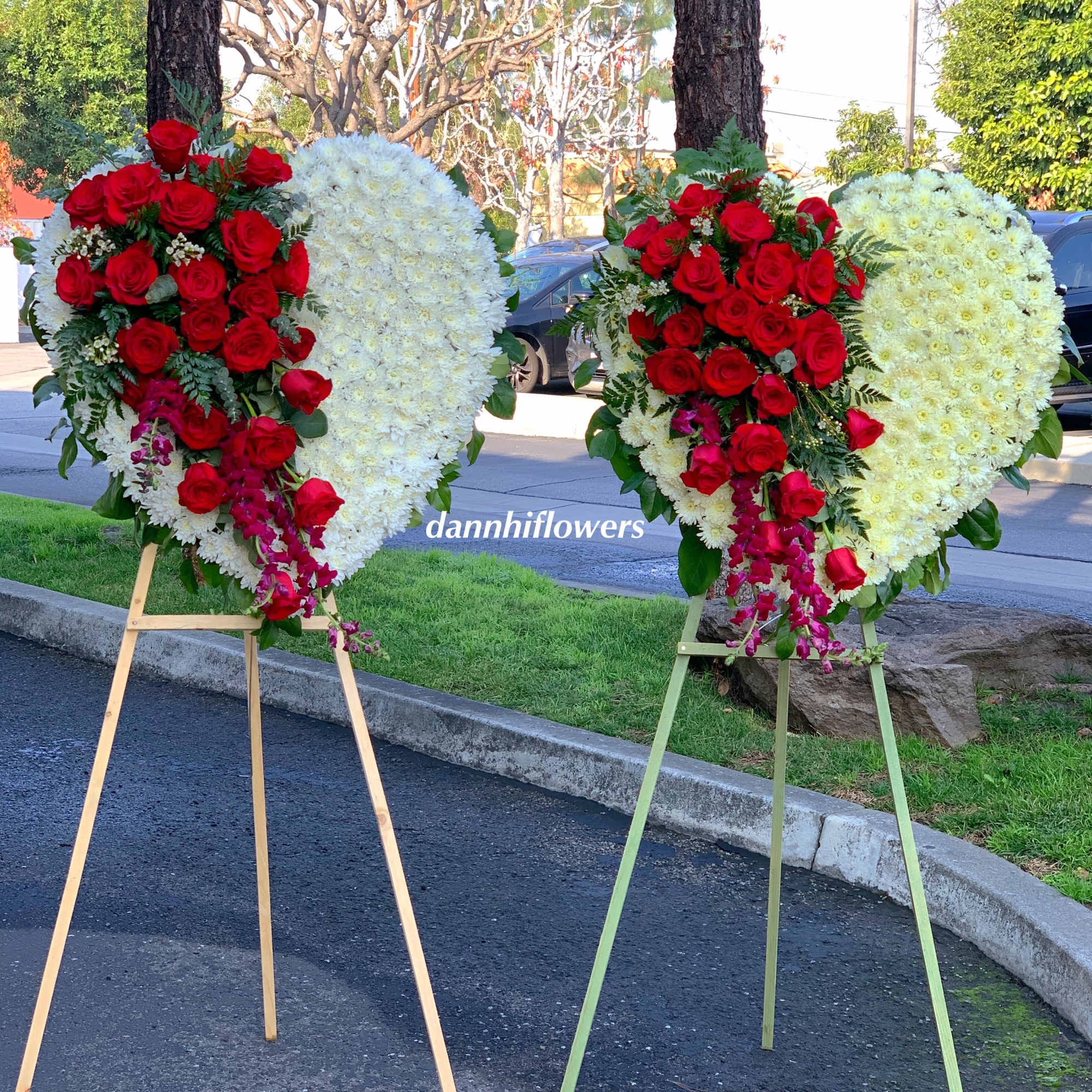 Two heart-shaped floral stands with red roses and white flowers