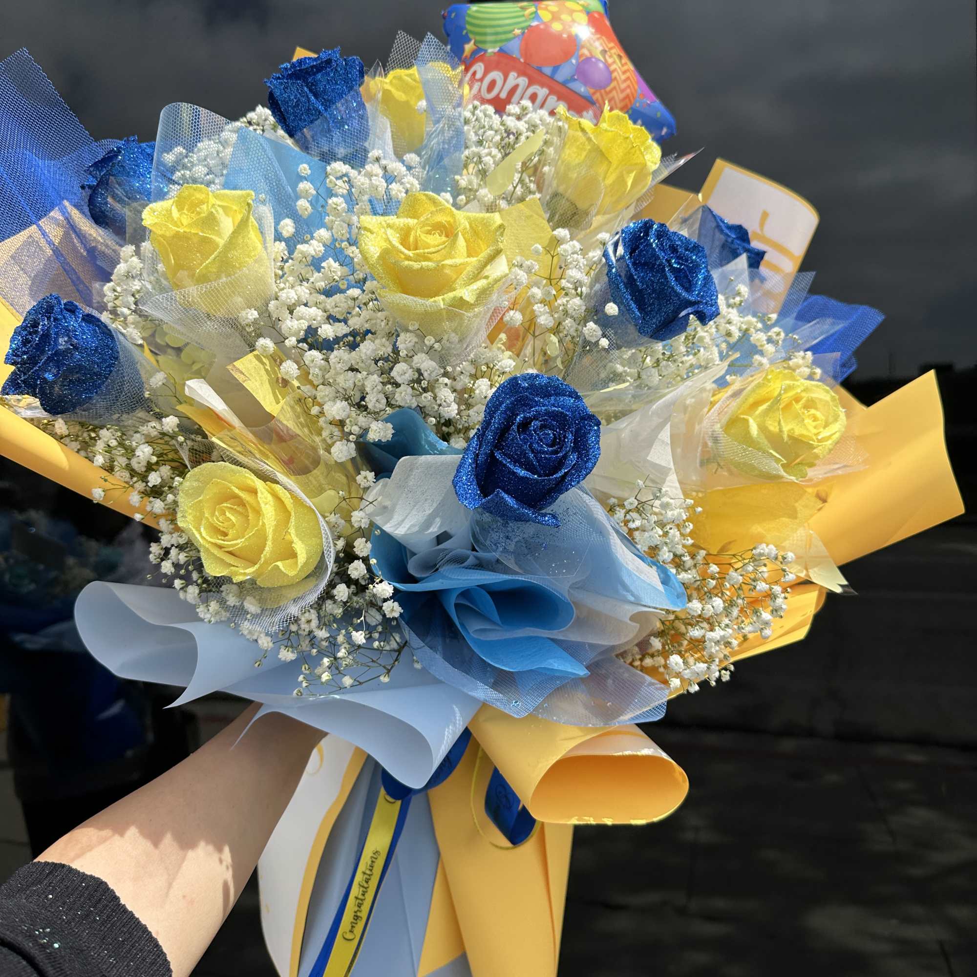 Bouquet of blue and yellow roses with baby's breath and colorful wrapping
