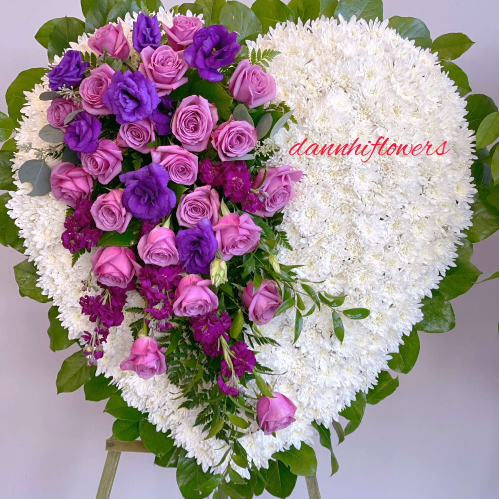 Heart-shaped floral wreath with pink and purple roses on white blooms