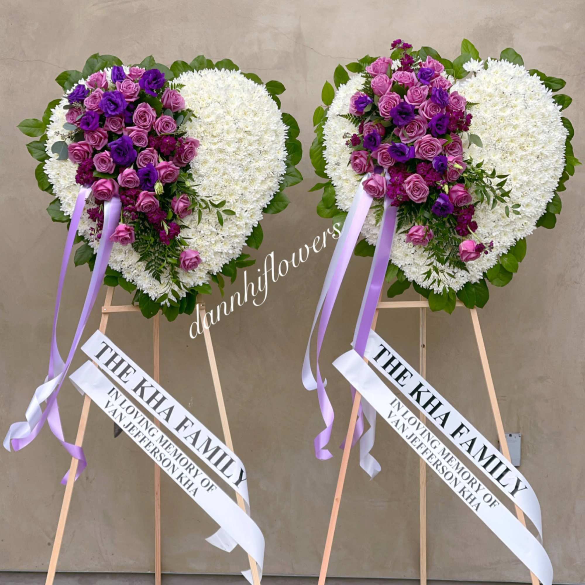 Two heart-shaped floral standing sprays with purple roses and white blooms