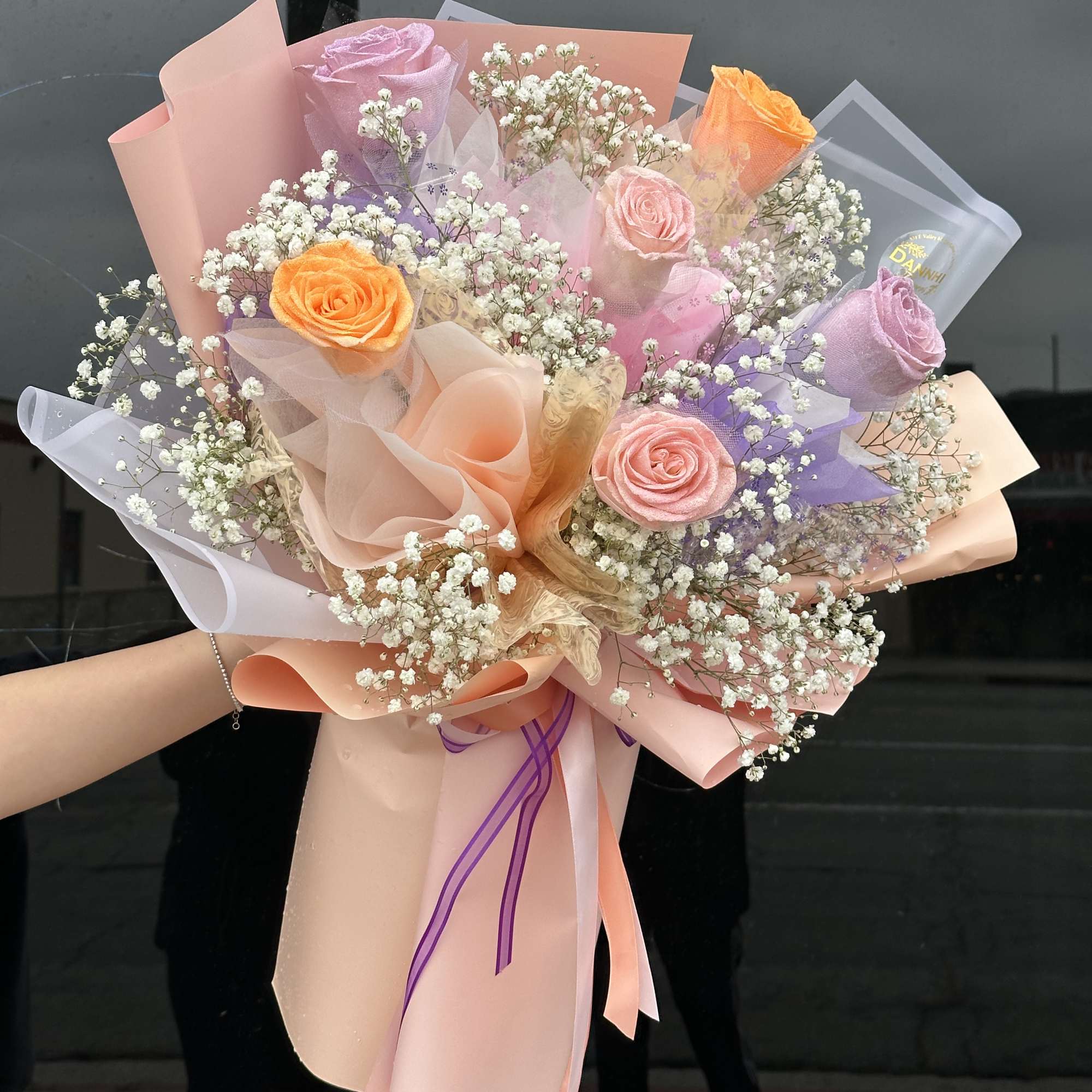 Bouquet of pastel roses with baby's breath in pink and lavender wrap