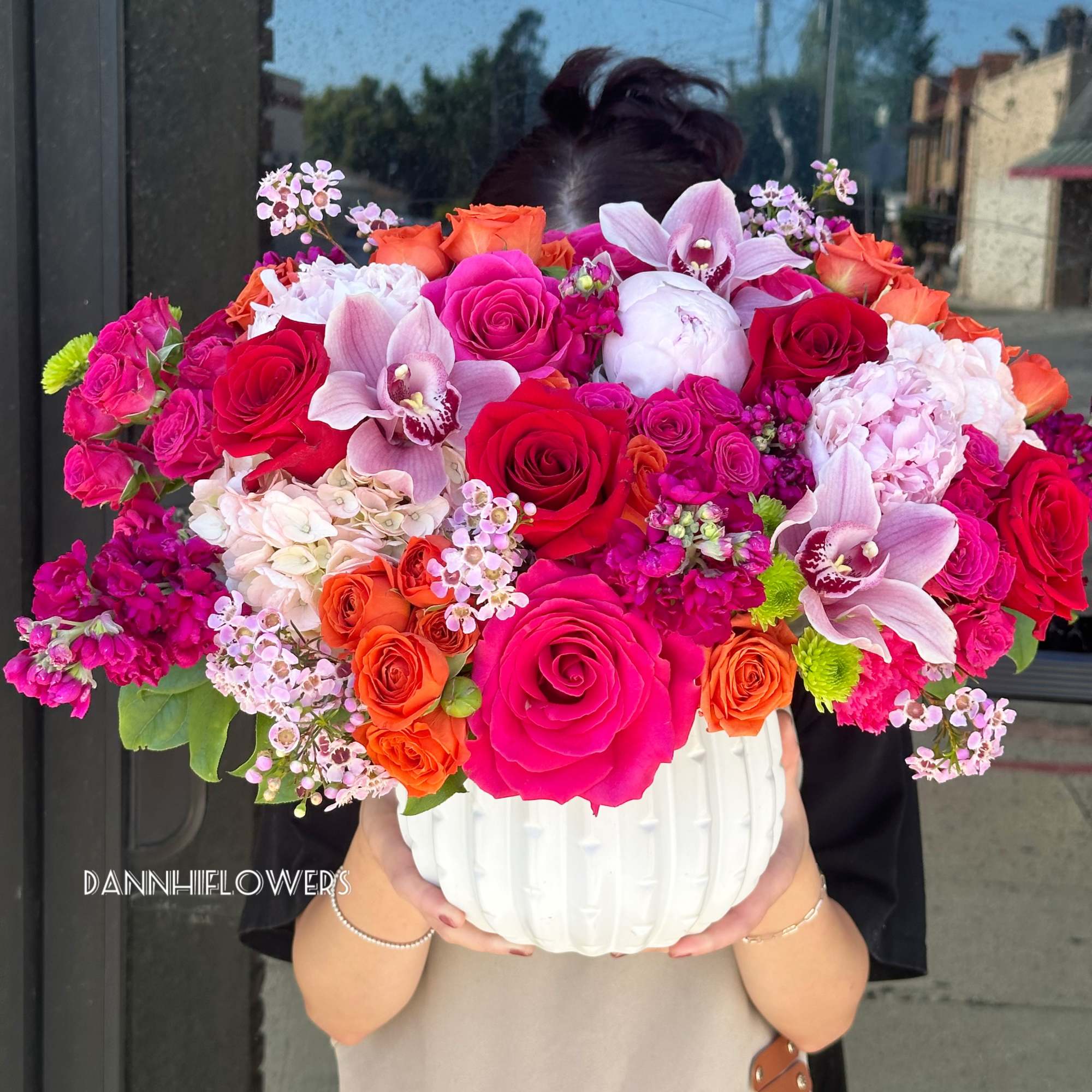 Large mixed bouquet in a white vase with pink, red, and orange blooms