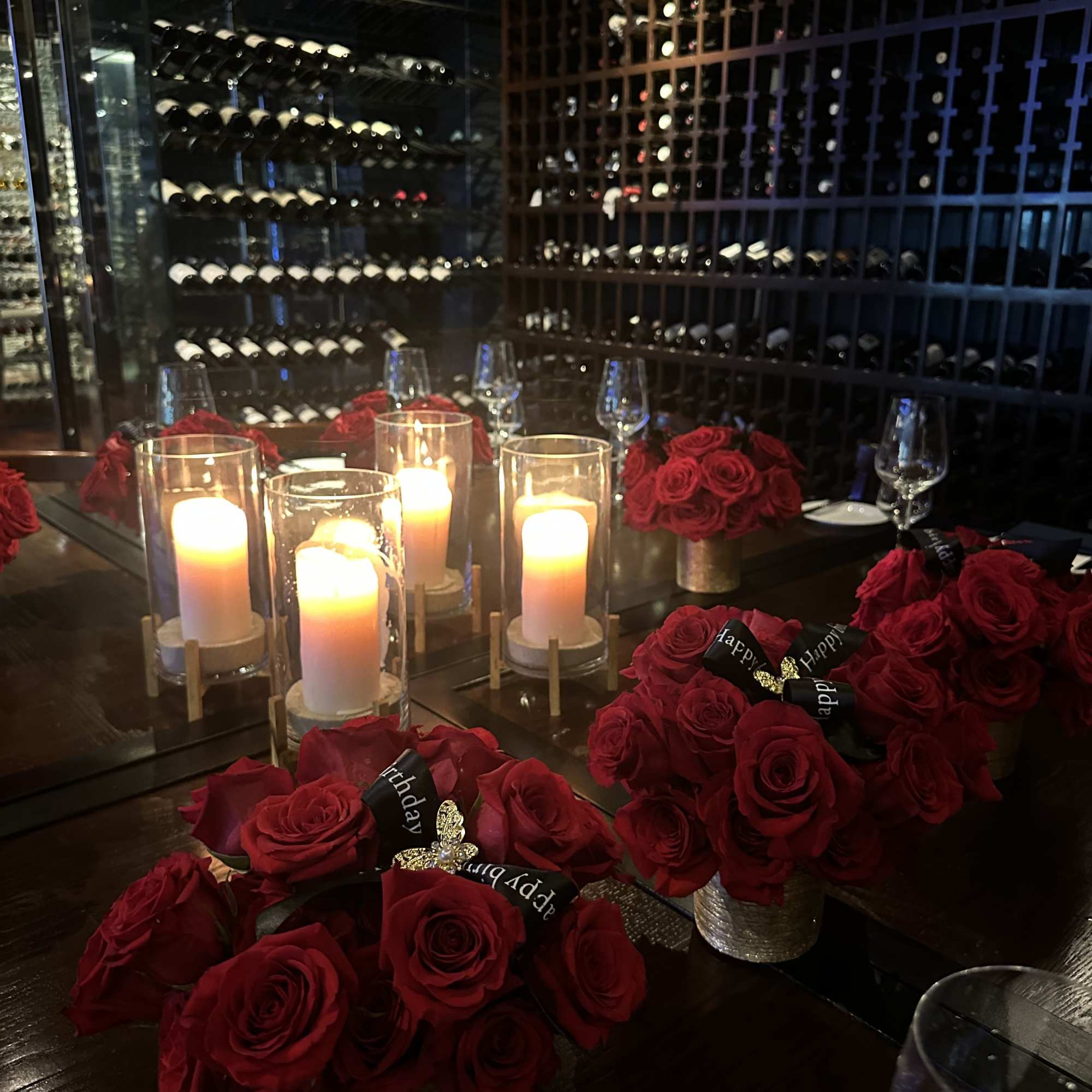 Red rose centerpieces with lit candles on a dining table