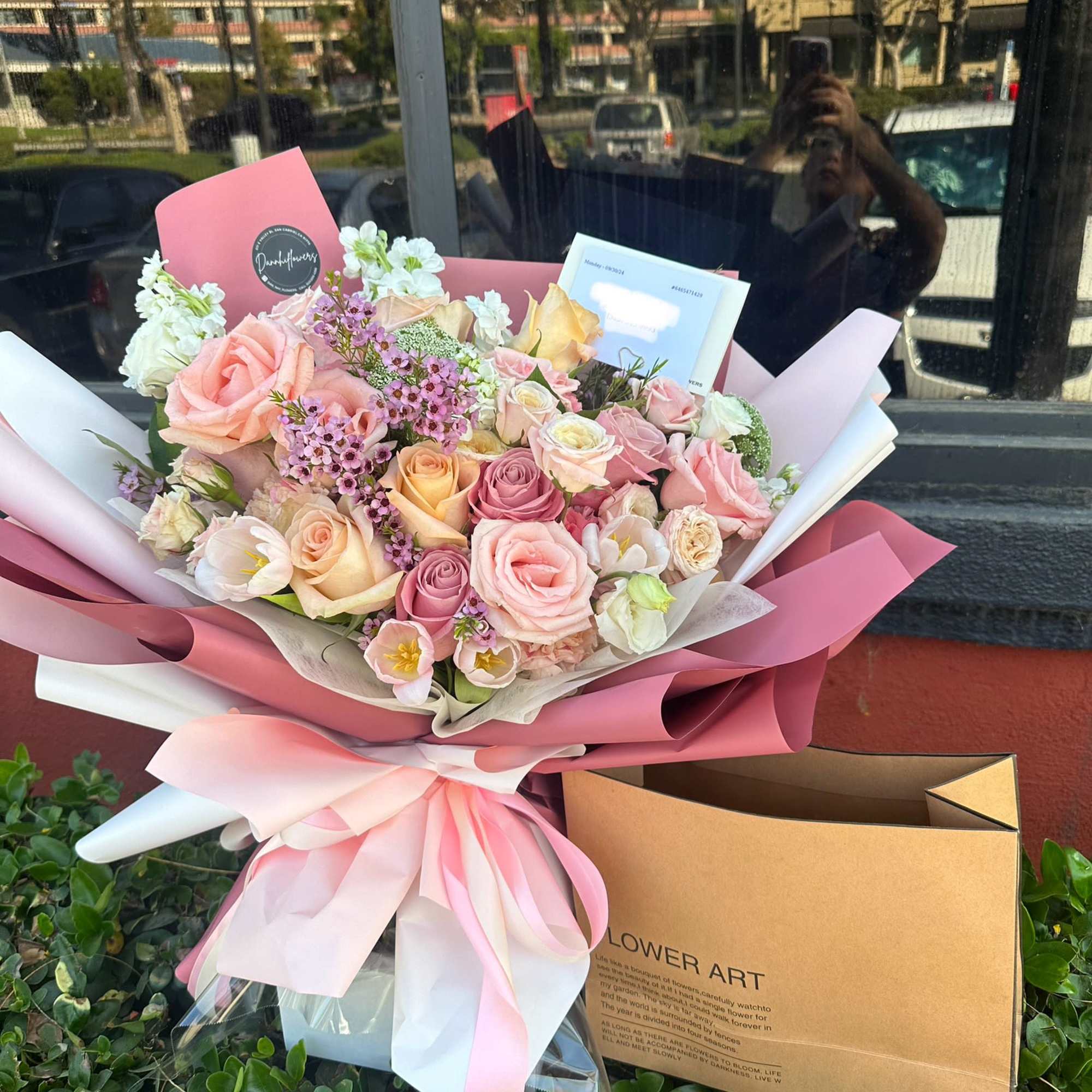 Pink and white rose bouquet wrapped in pink paper with a ribbon