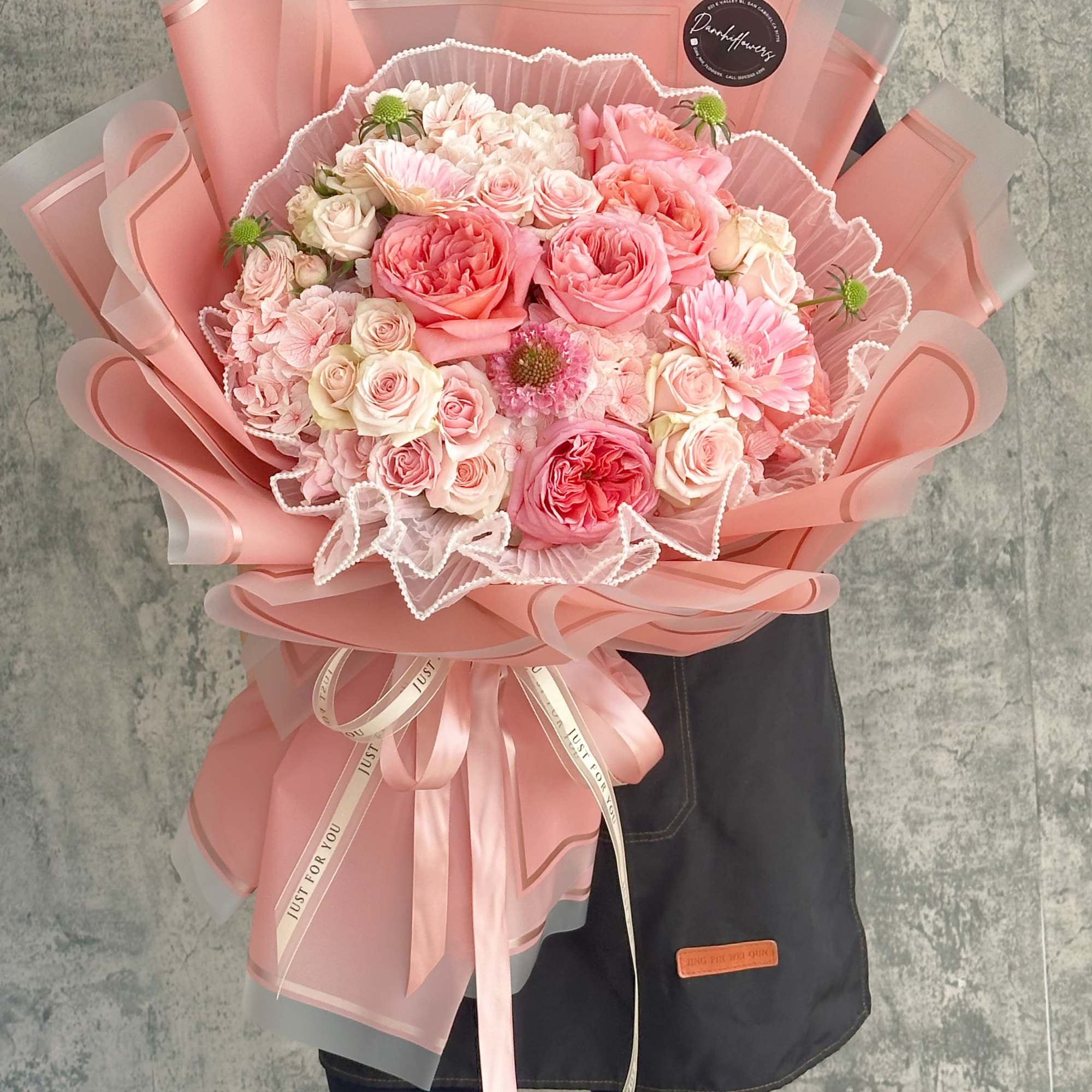 Large pink bouquet of roses and daisies wrapped in pink paper