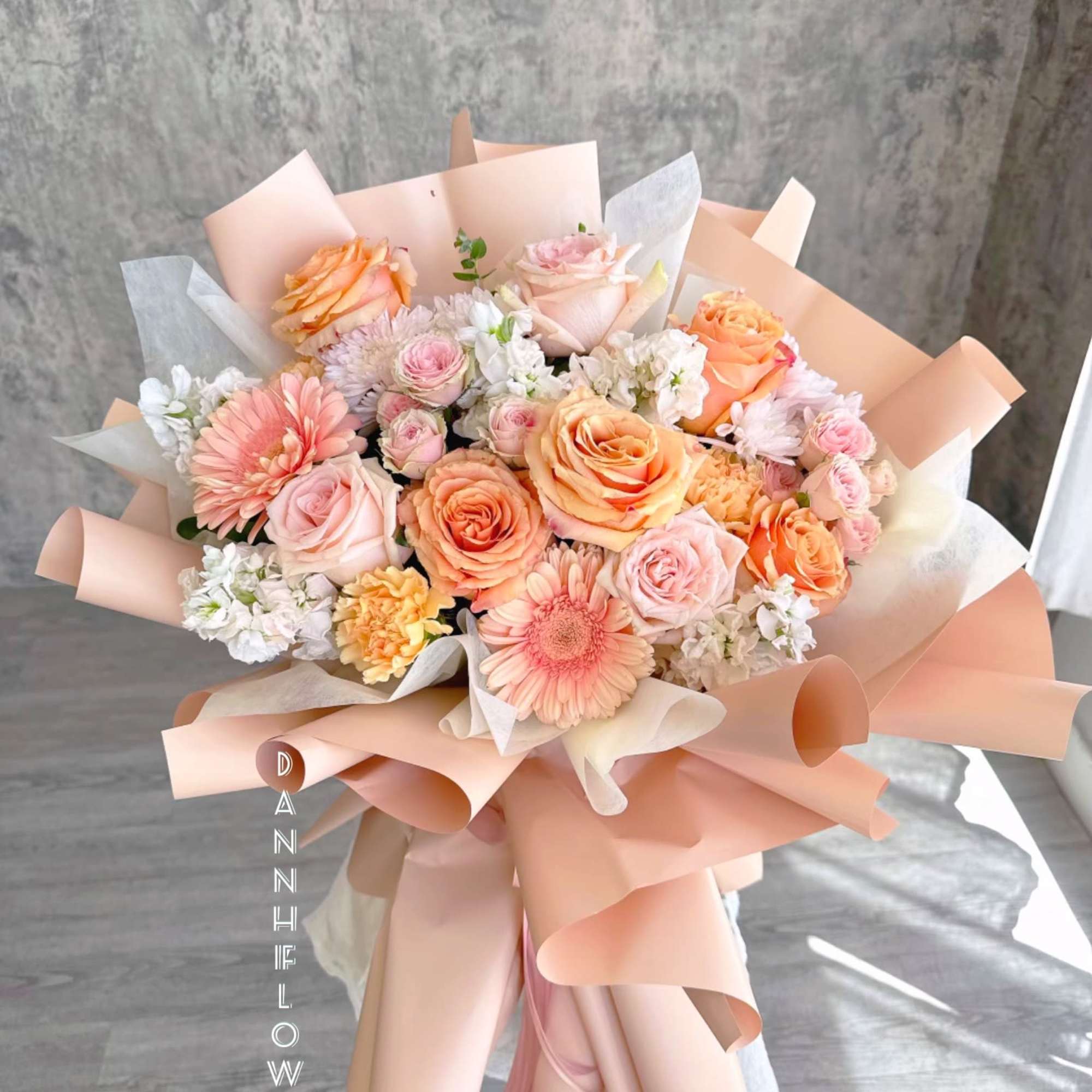 Peach and pink mixed bouquet with roses and daisies wrapped in blush paper