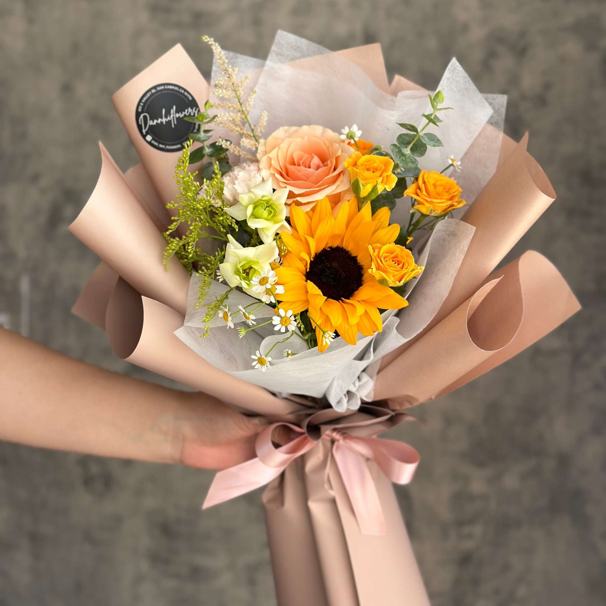 Hand-tied bouquet with a sunflower, peach rose, and yellow spray roses