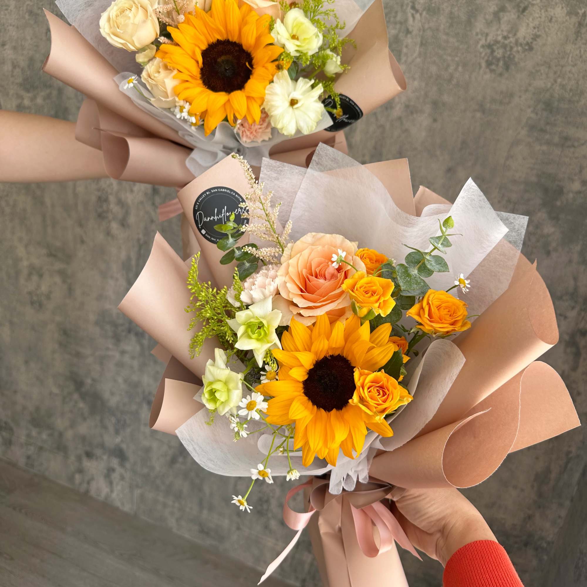 Two hand-tied bouquets with sunflowers, roses, and pastel wrapping paper