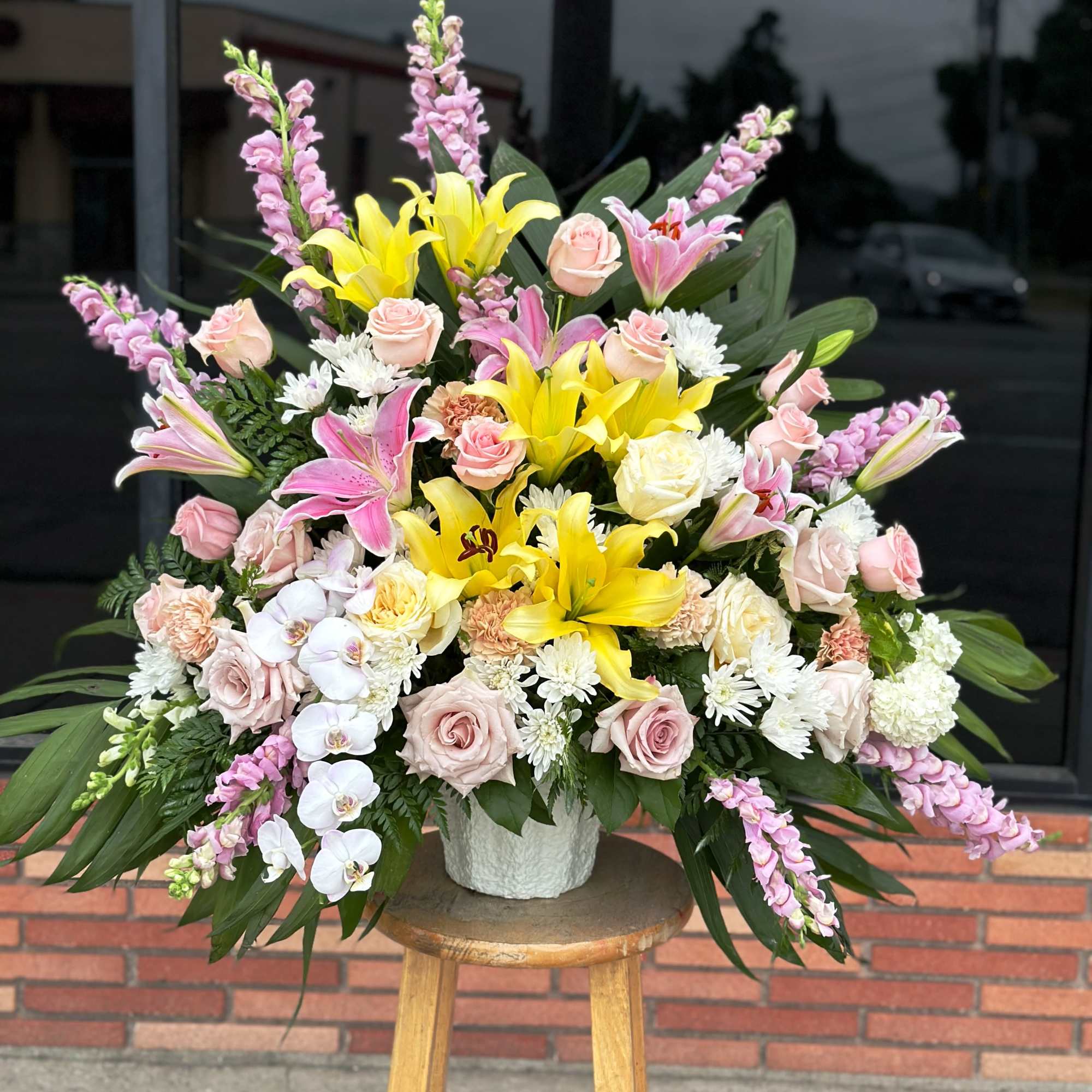 Large bouquet of yellow lilies, pink roses, and orchids in a white vase