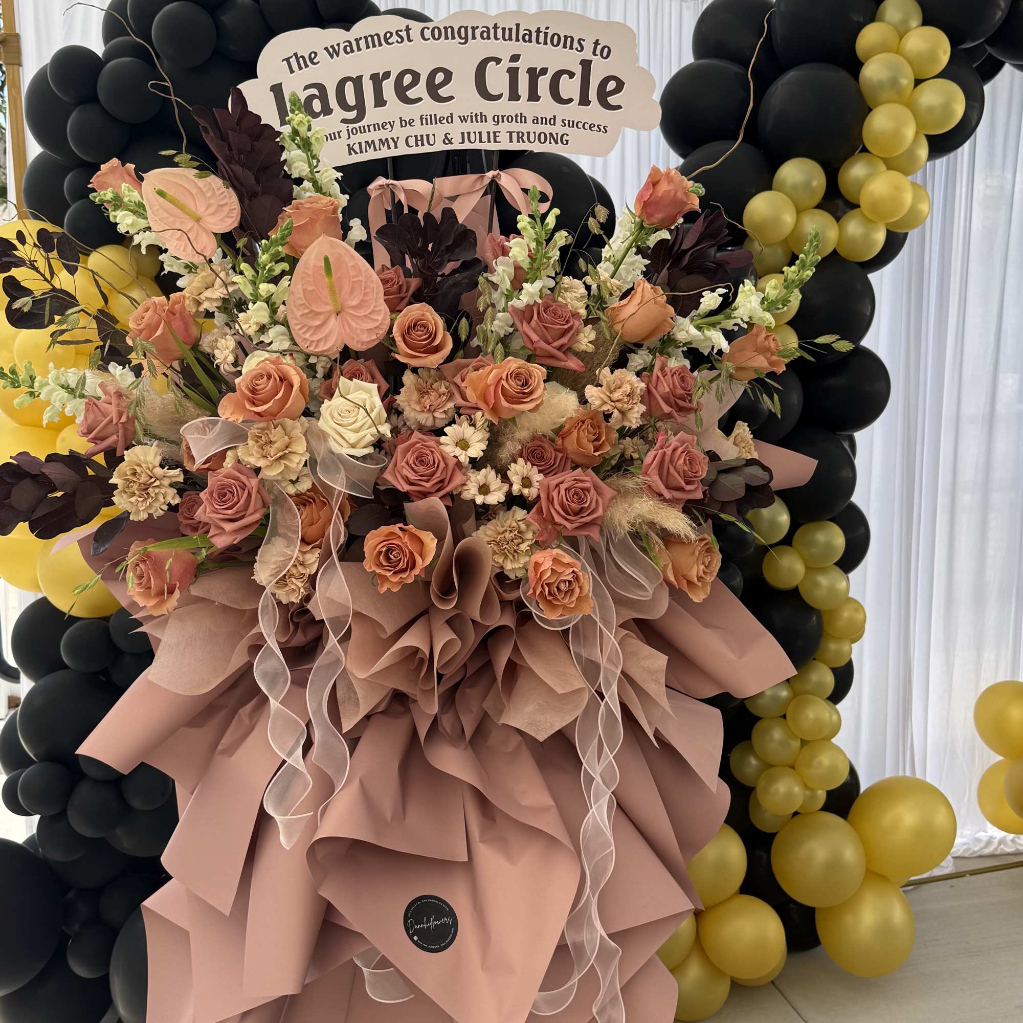 Large peach and blush floral arrangement with black and gold balloons