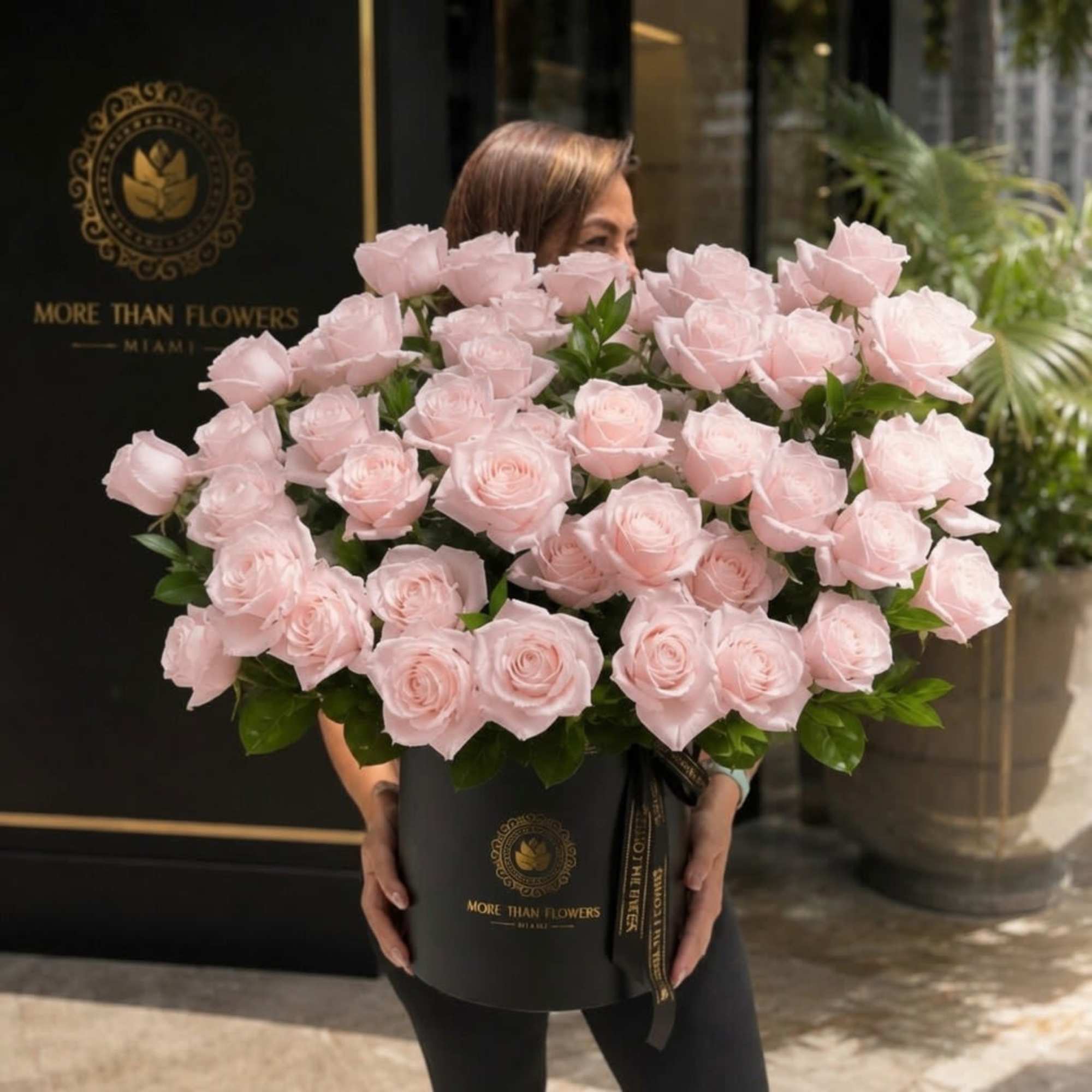 Forty pale blush roses gathered in a sleek black hatbox make a