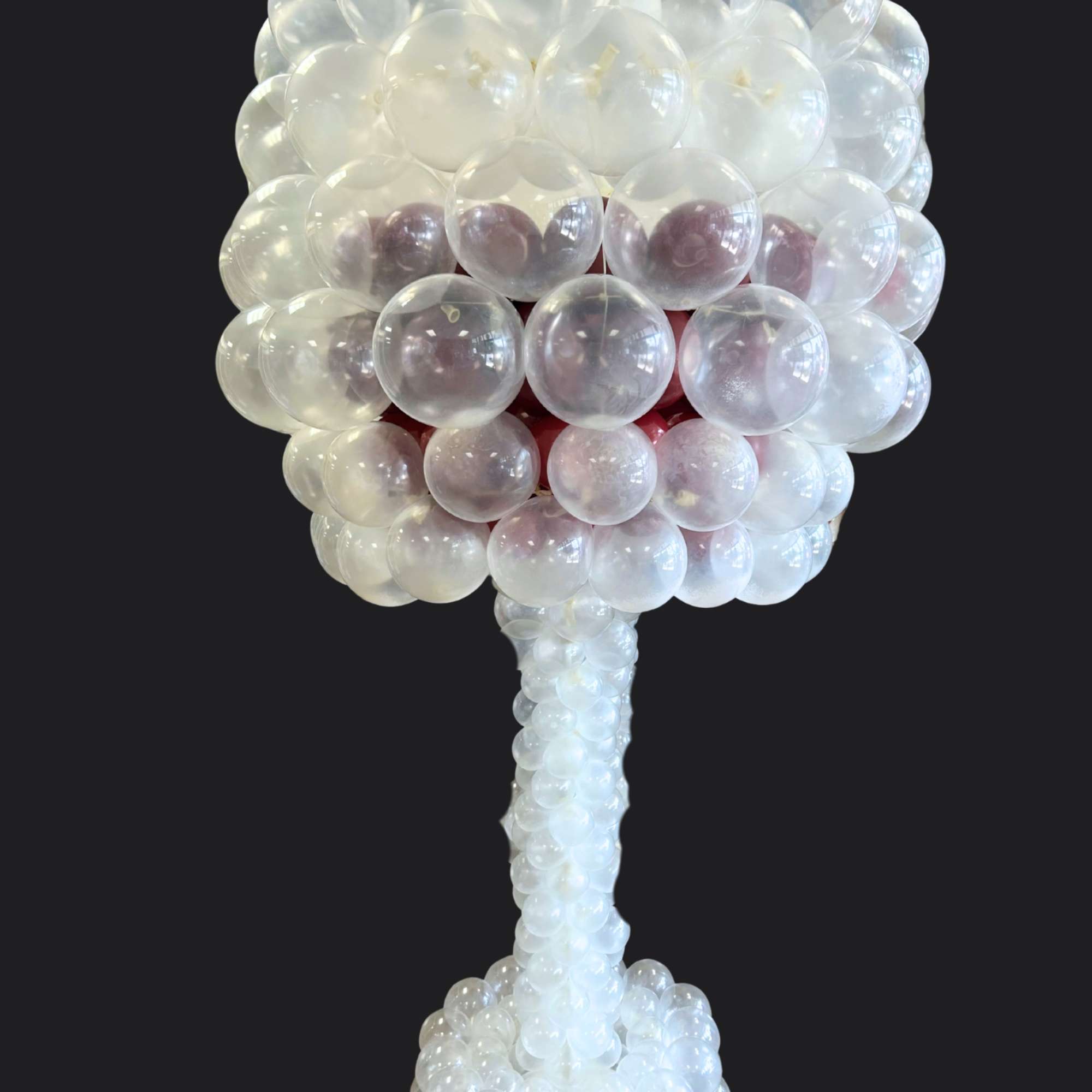Clear balloon sculpture shaped like a tree on a black background