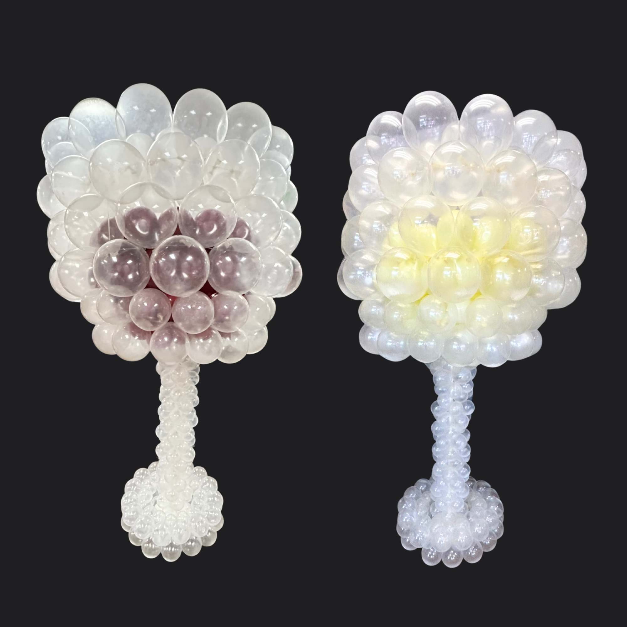 Two clear balloon topiary arrangements with round bases on a dark background.