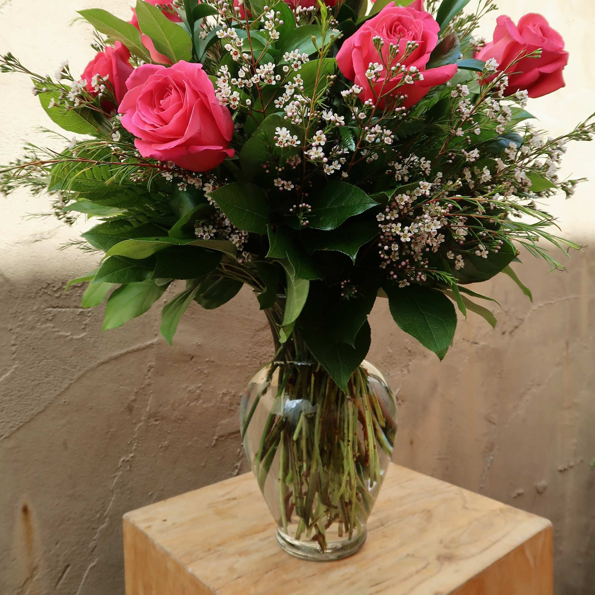 Pink roses arranged in a clear glass vase with small white filler flowers, photo 2 of 2