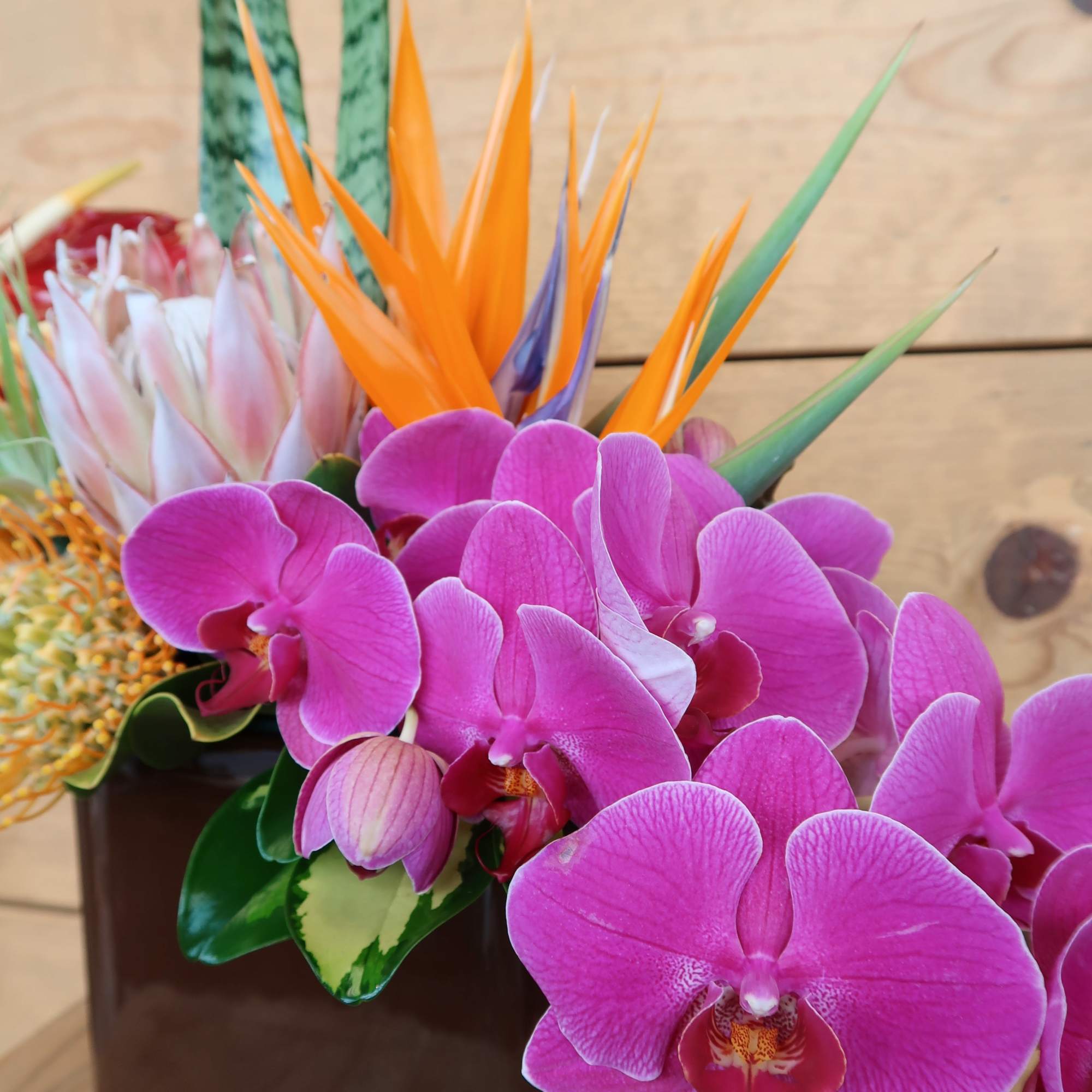 An assortment of tropical blooms in a brown ceramic vase, perfect to, photo 4 of 4