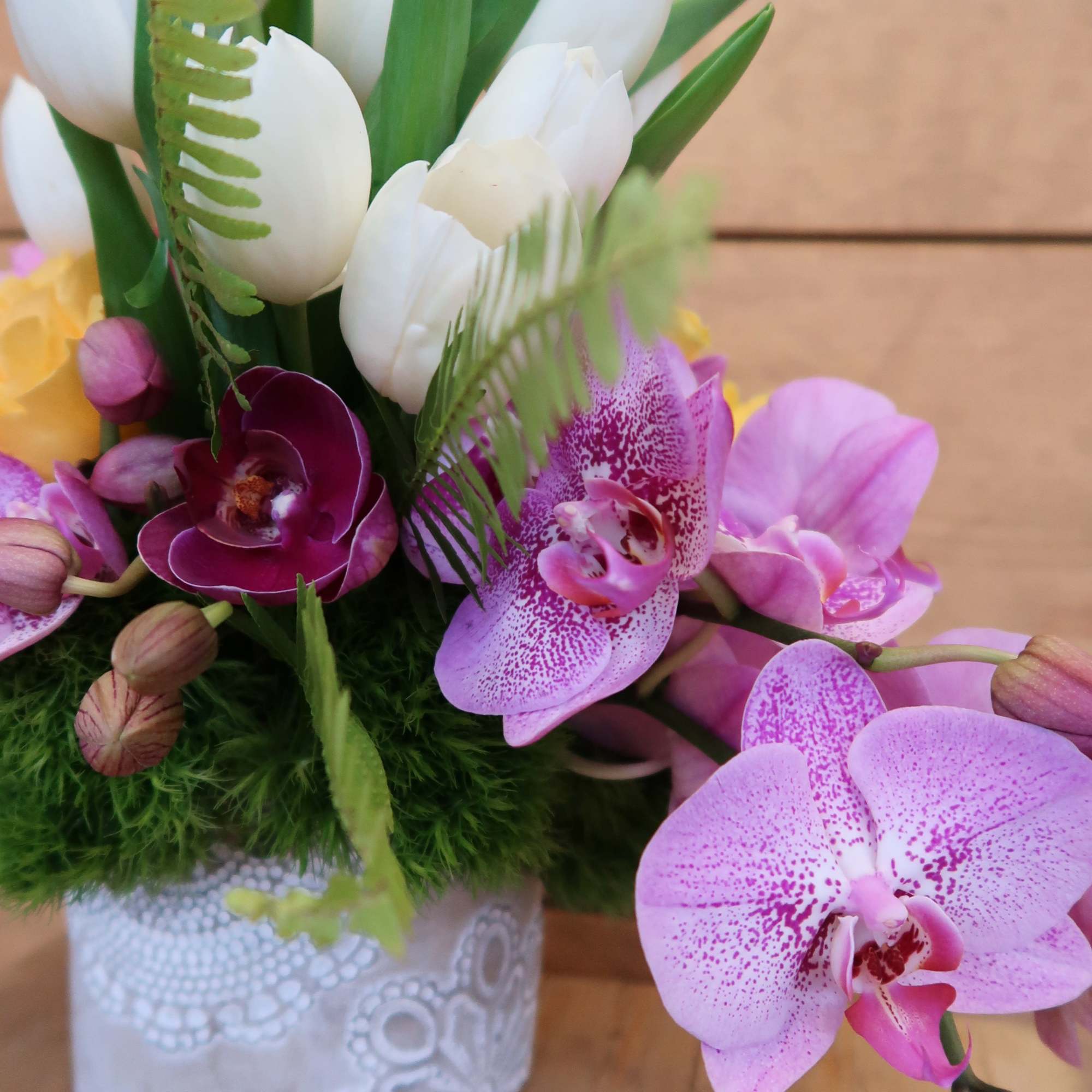 White tulips and pink orchids arranged in a decorative pot.