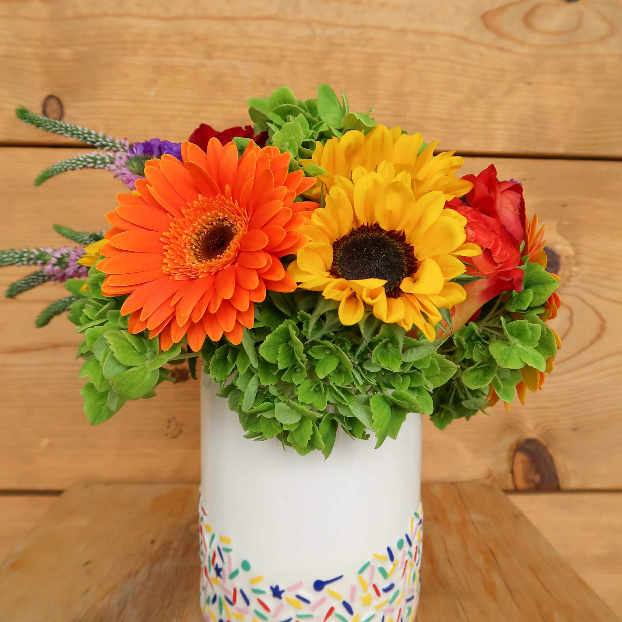 Bright mixed bouquet in a white vase with colorful sprinkles