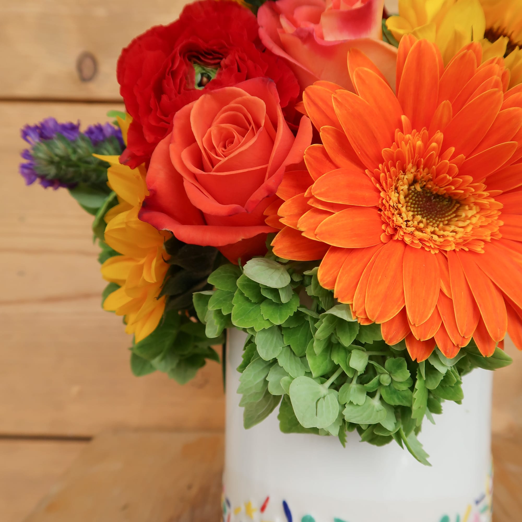 Colorful bouquet of roses and gerbera daisies in a white vase