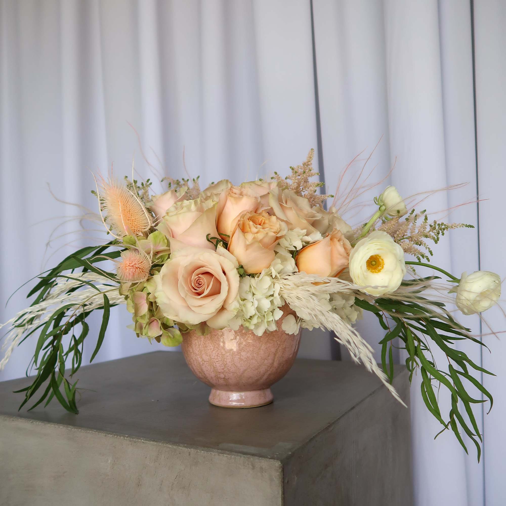 Peach and cream rose arrangement in a pink vase