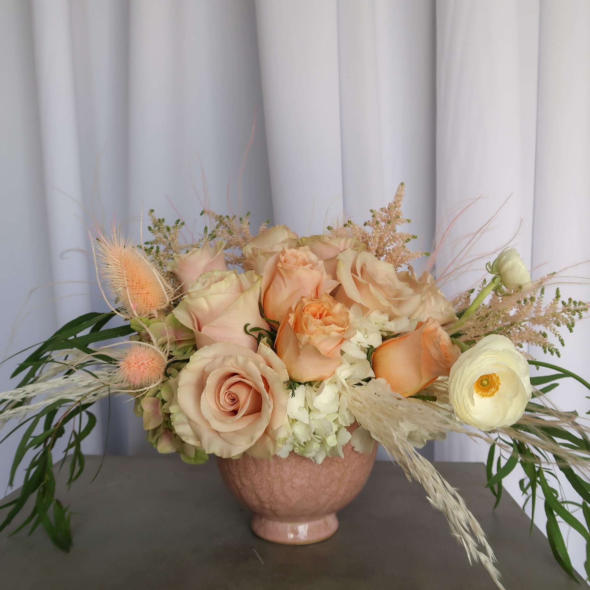 Peach and cream floral arrangement in a pink vase