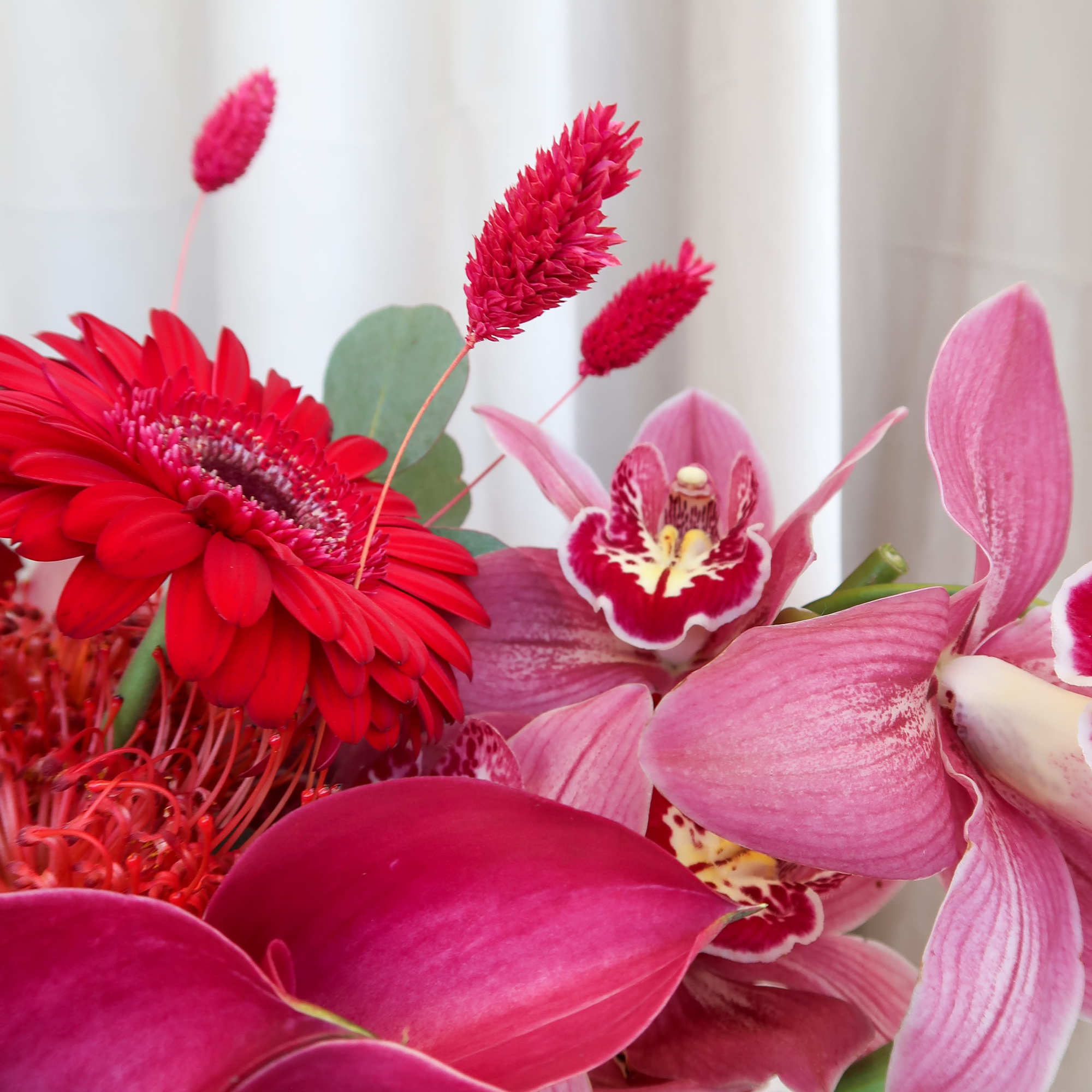 Pink and red bouquet with orchids, calla lilies, and a gerbera daisy