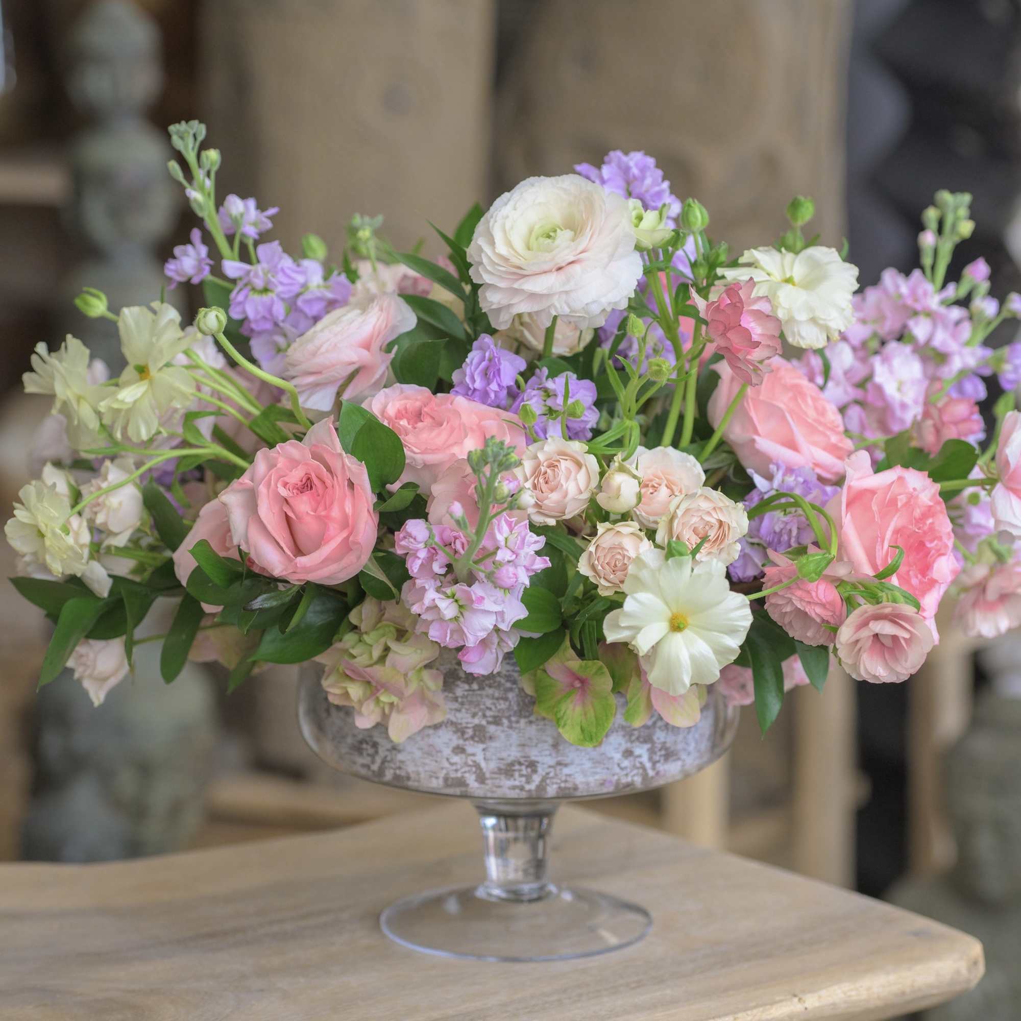 Pink and white flowers arranged in a glass pedestal vase