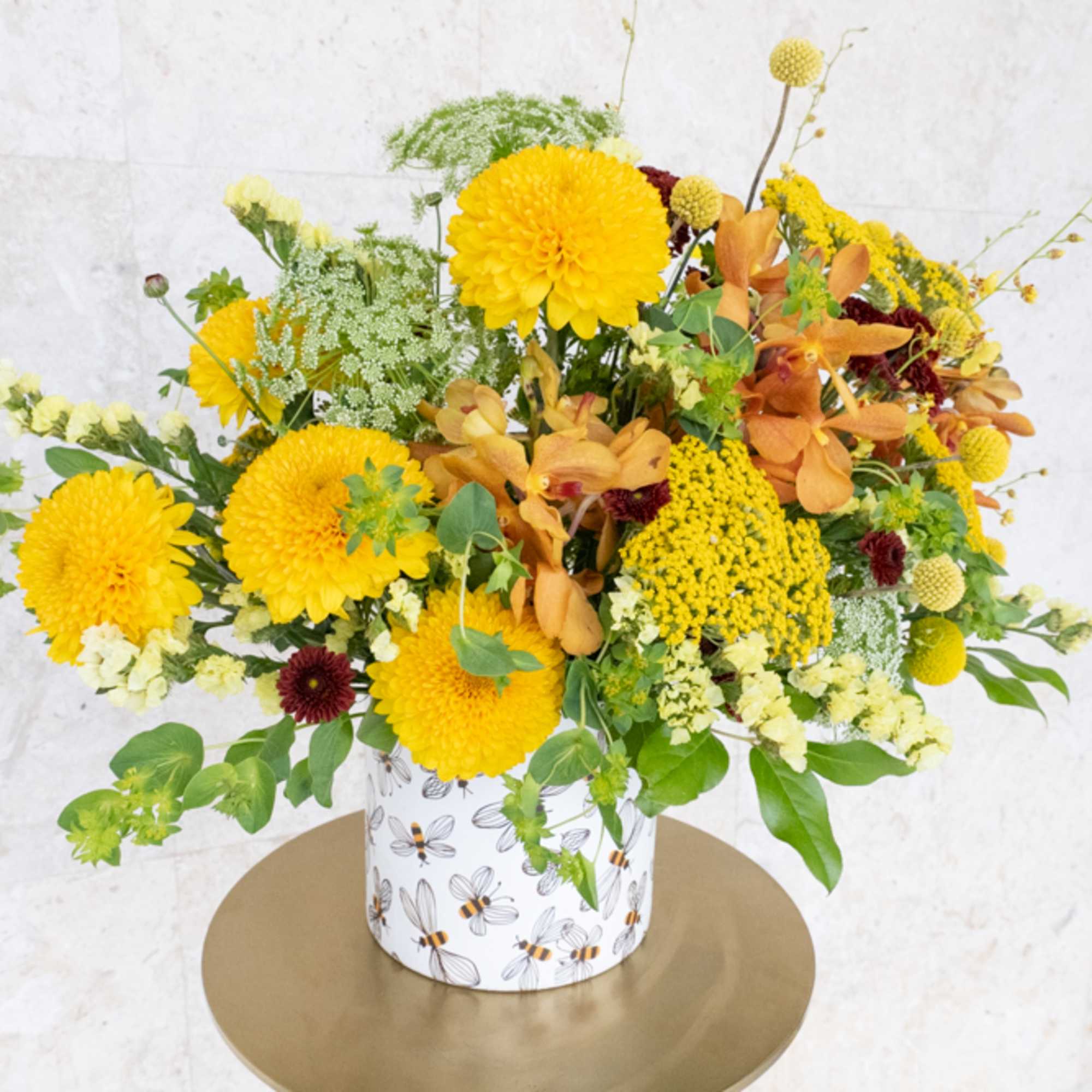 Yellow and orange floral arrangement in a patterned container