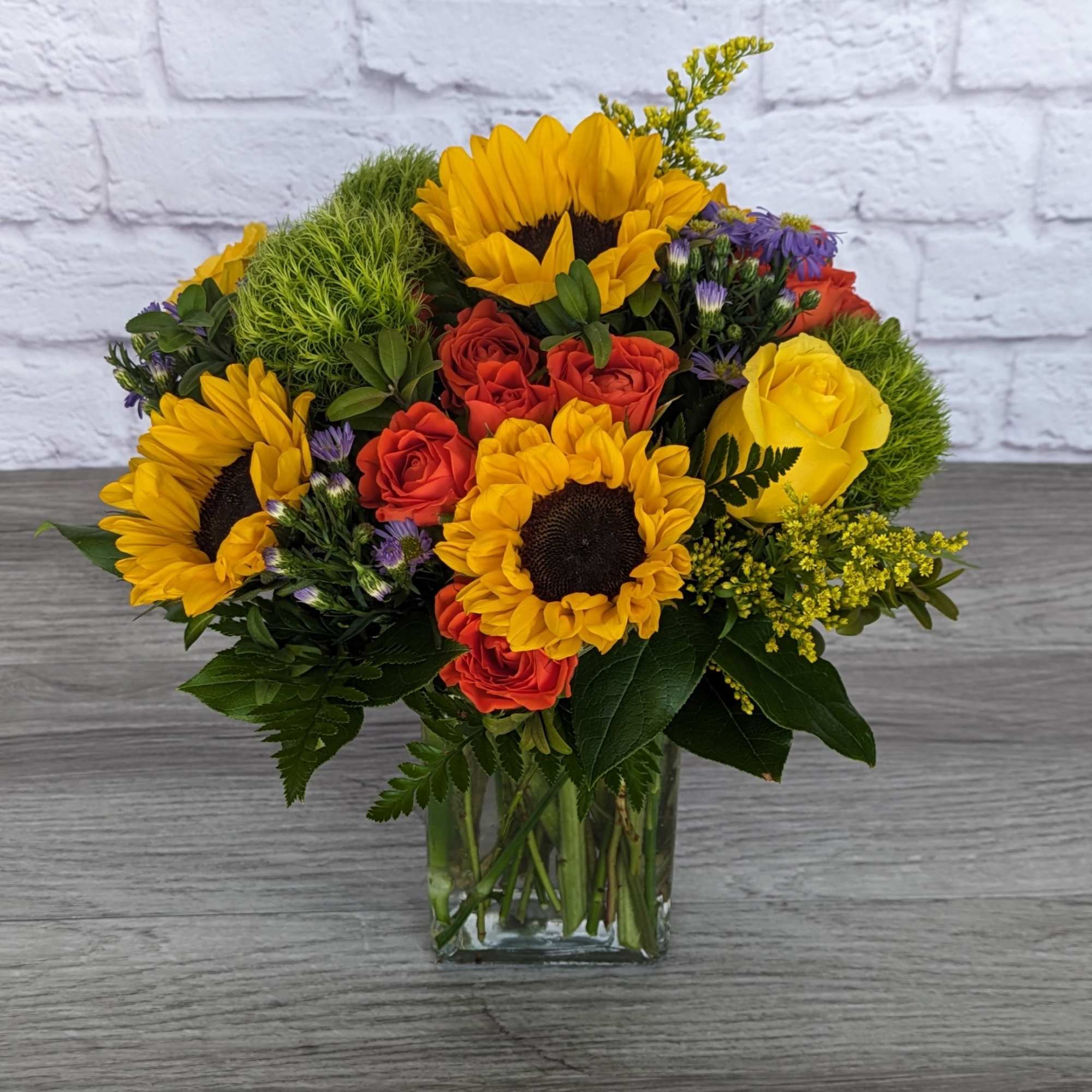 Bouquet of sunflowers and roses in a clear glass vase