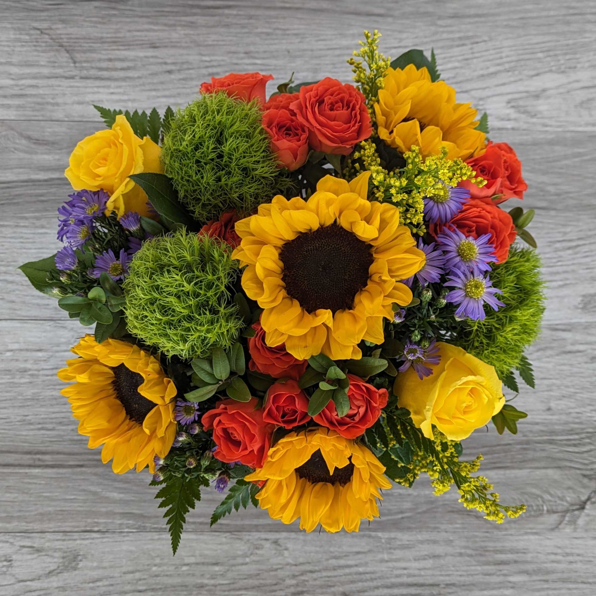 Bouquet of sunflowers, red roses, and purple daisies