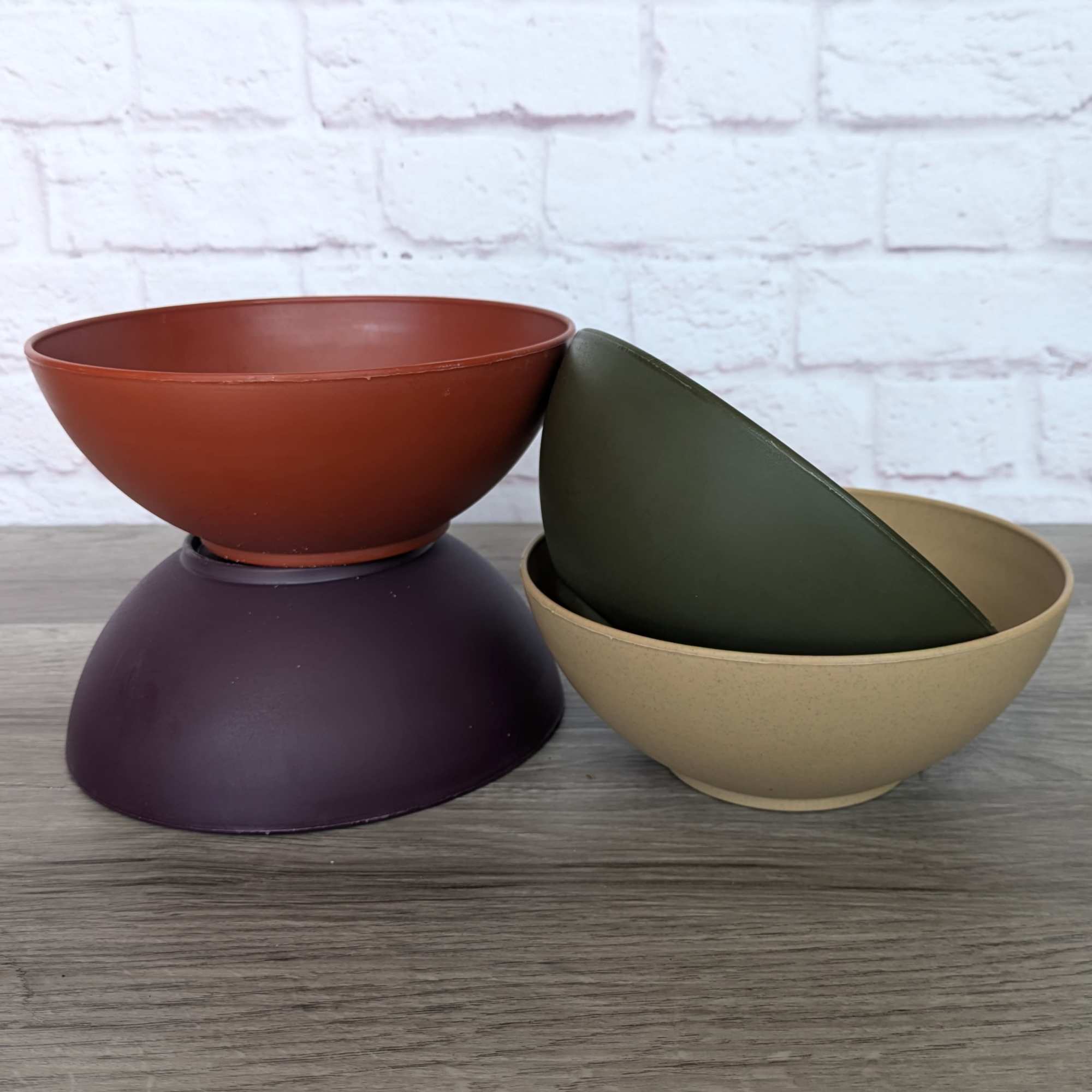 Stacked empty plastic bowls in rust, purple, green, and beige