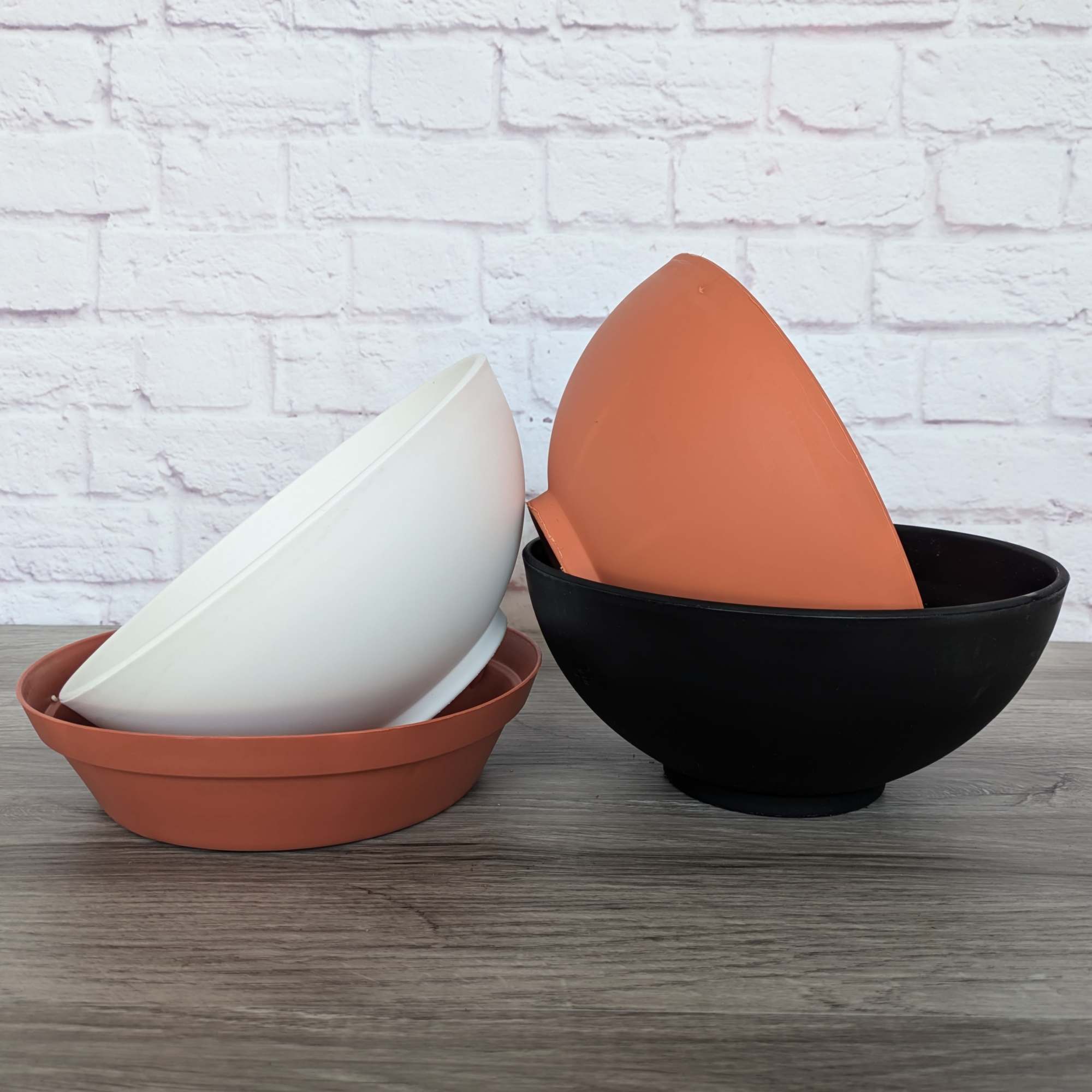 Three nested decorative bowls in terracotta, white, and black