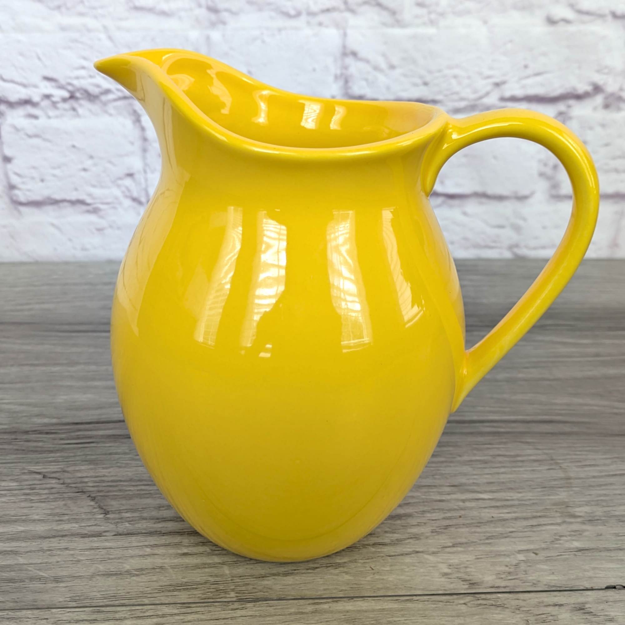 Yellow ceramic pitcher on a wooden surface