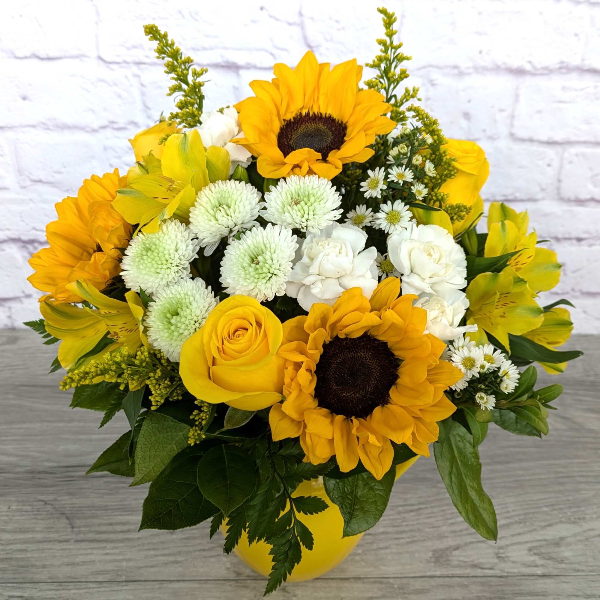 Yellow sunflowers and roses in a yellow vase with white blooms