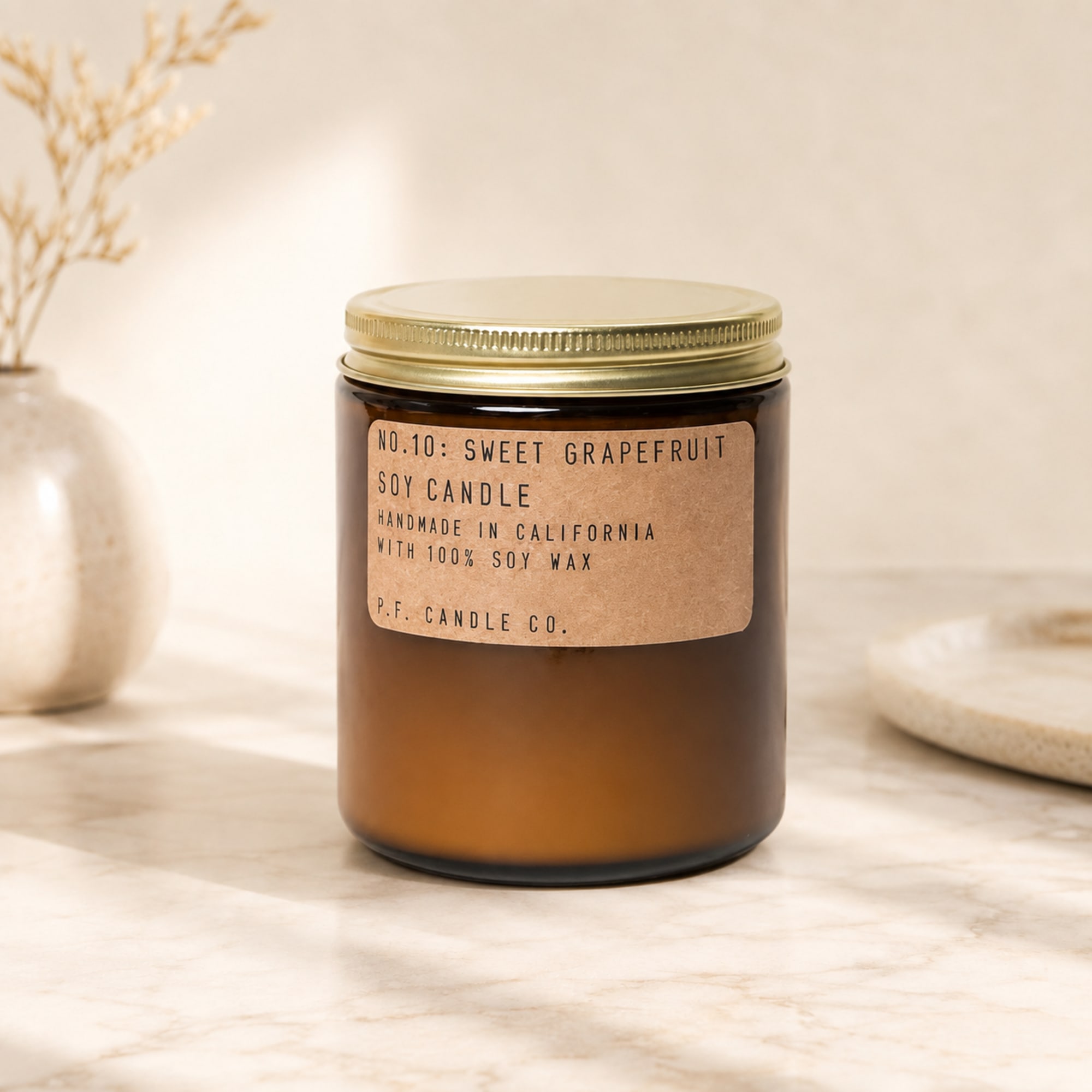 Amber jar candle with a gold lid and paper label
