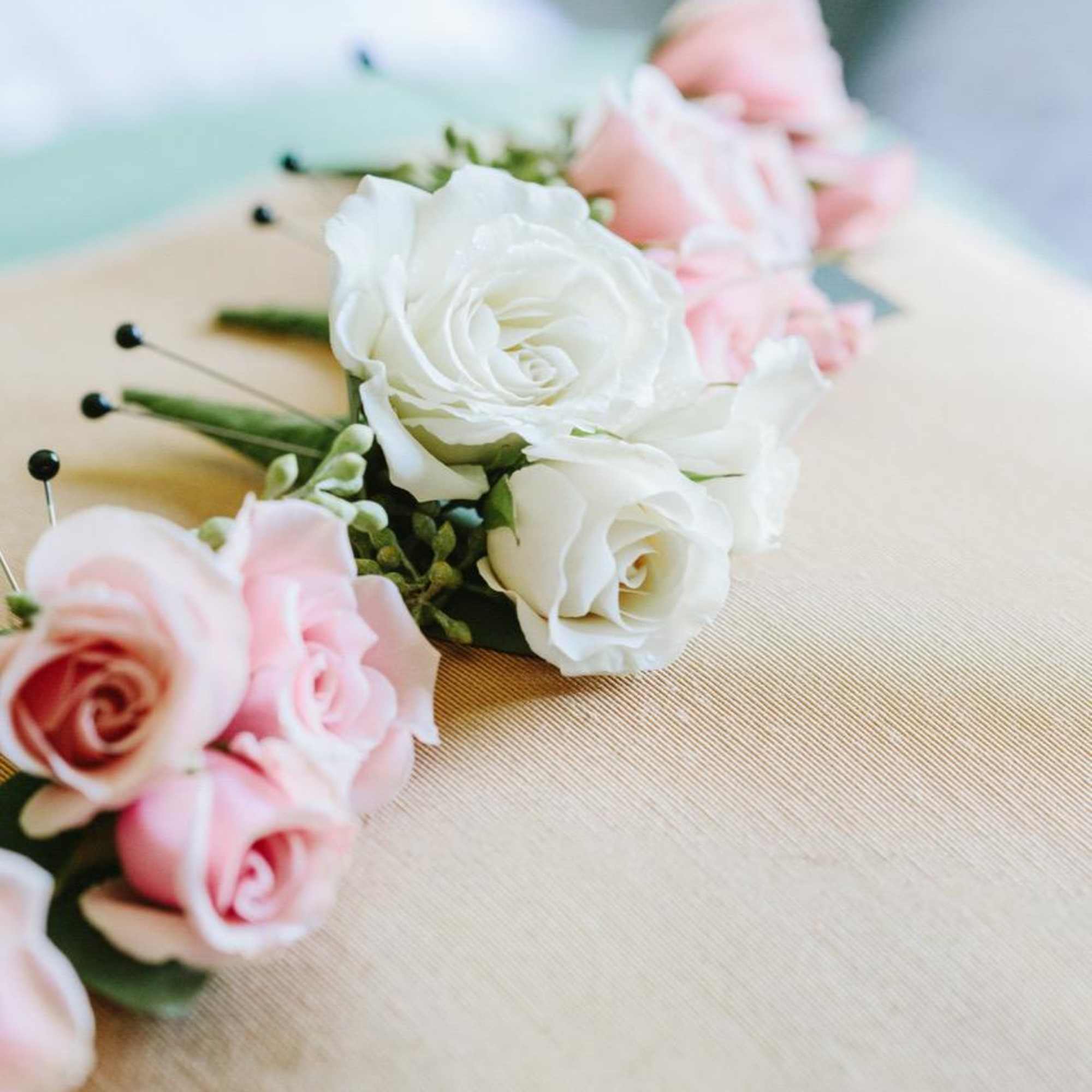 Pink and white rose boutonnieres on a beige surface