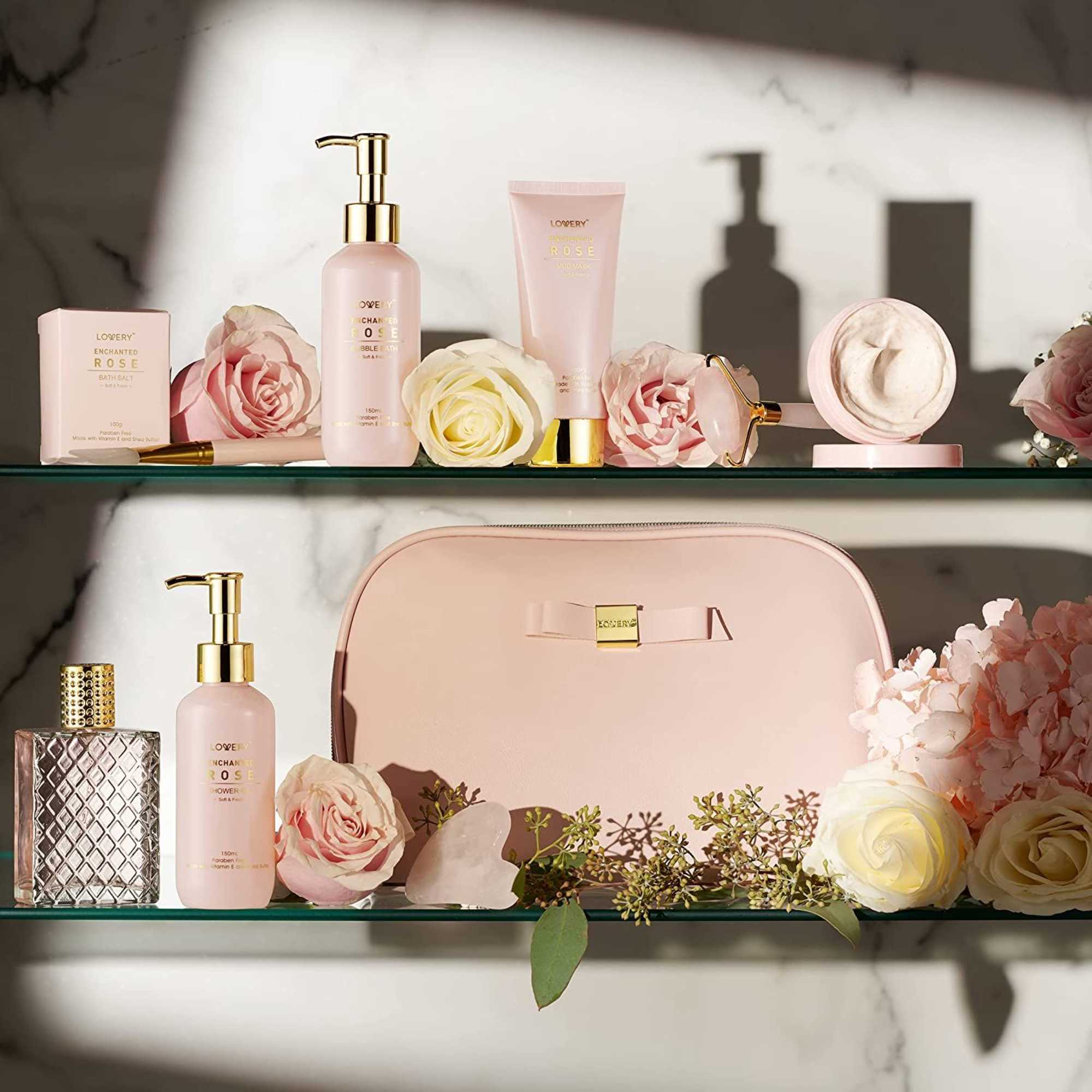 Pink bath and body gift set with cosmetic bag arranged with pale roses on glass shelves.