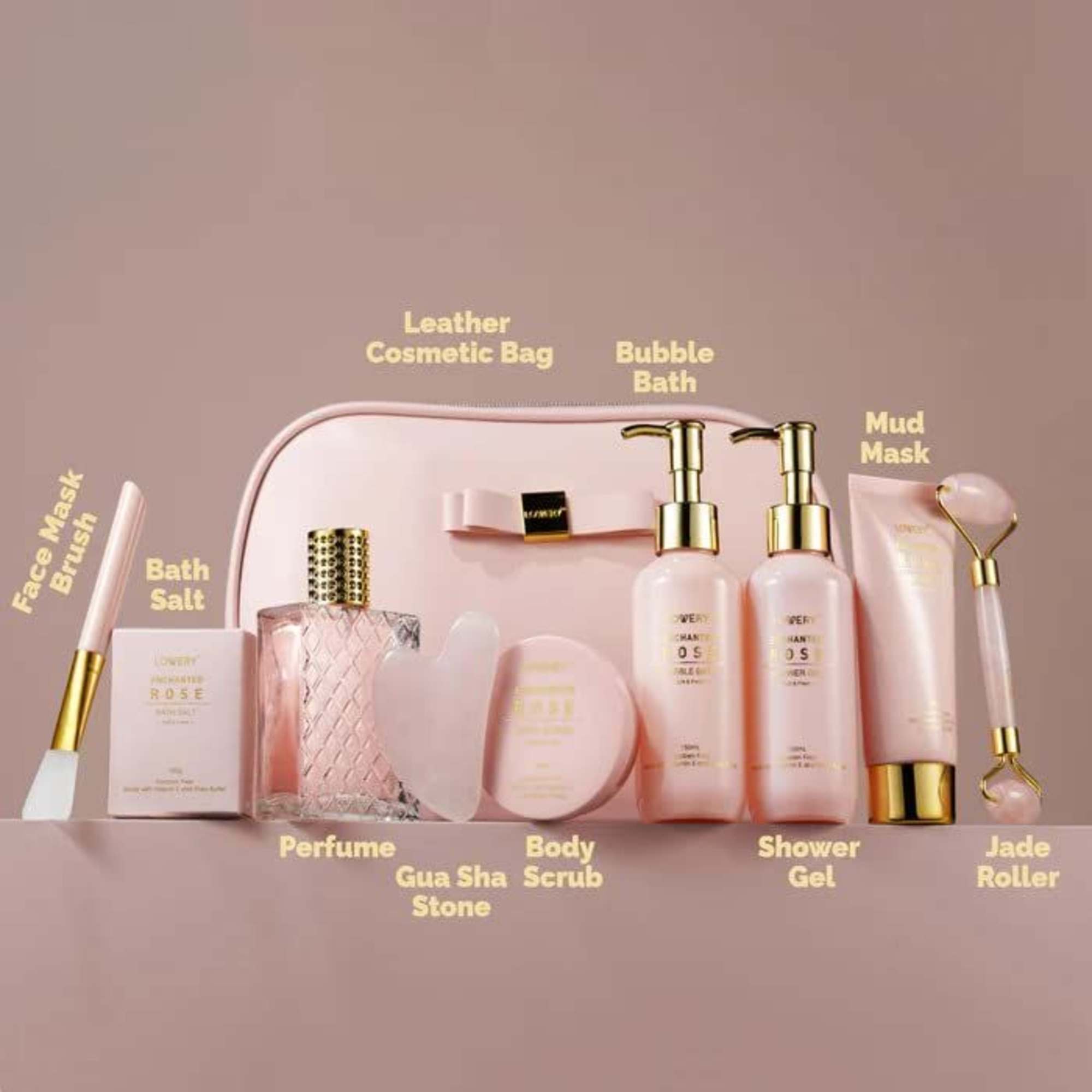 Pink bath and body gift set with cosmetic bag, bottles, and skincare tools on a pink surface.