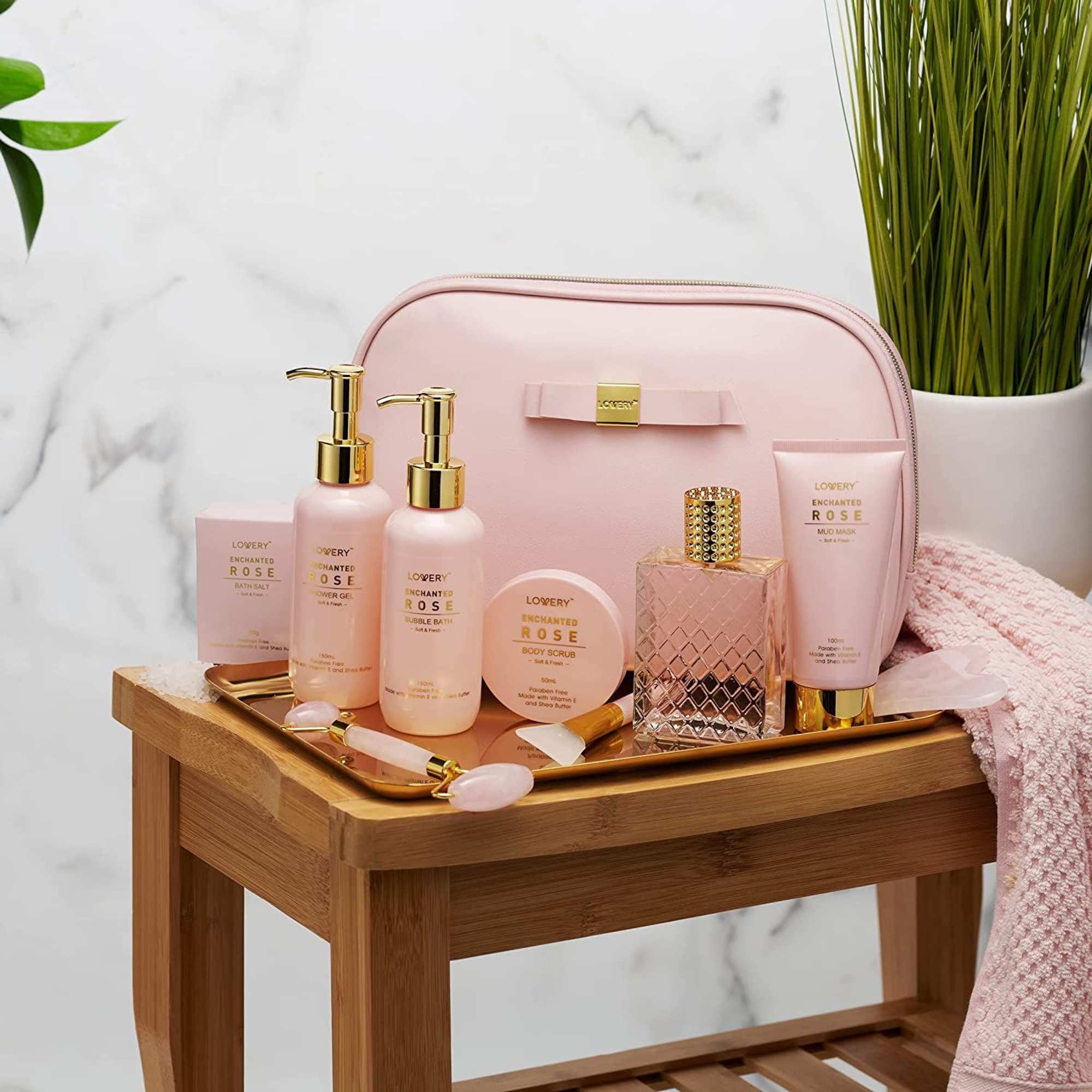 Pink rose-scented bath and body gift set with cosmetic bag and bottles on a wooden bench
