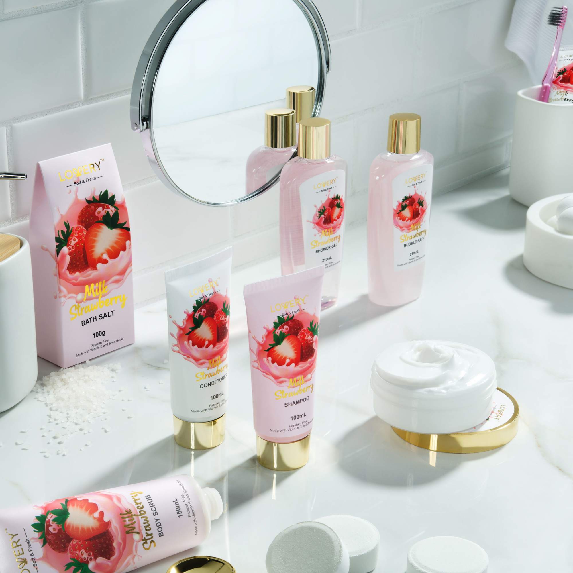 Strawberry-themed pink bath and body products arranged on a white bathroom counter.
