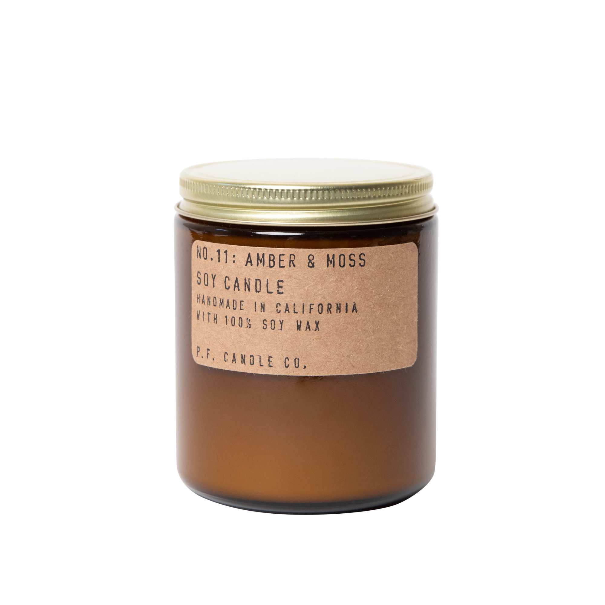 Amber candle in a glass jar with a gold lid and paper label