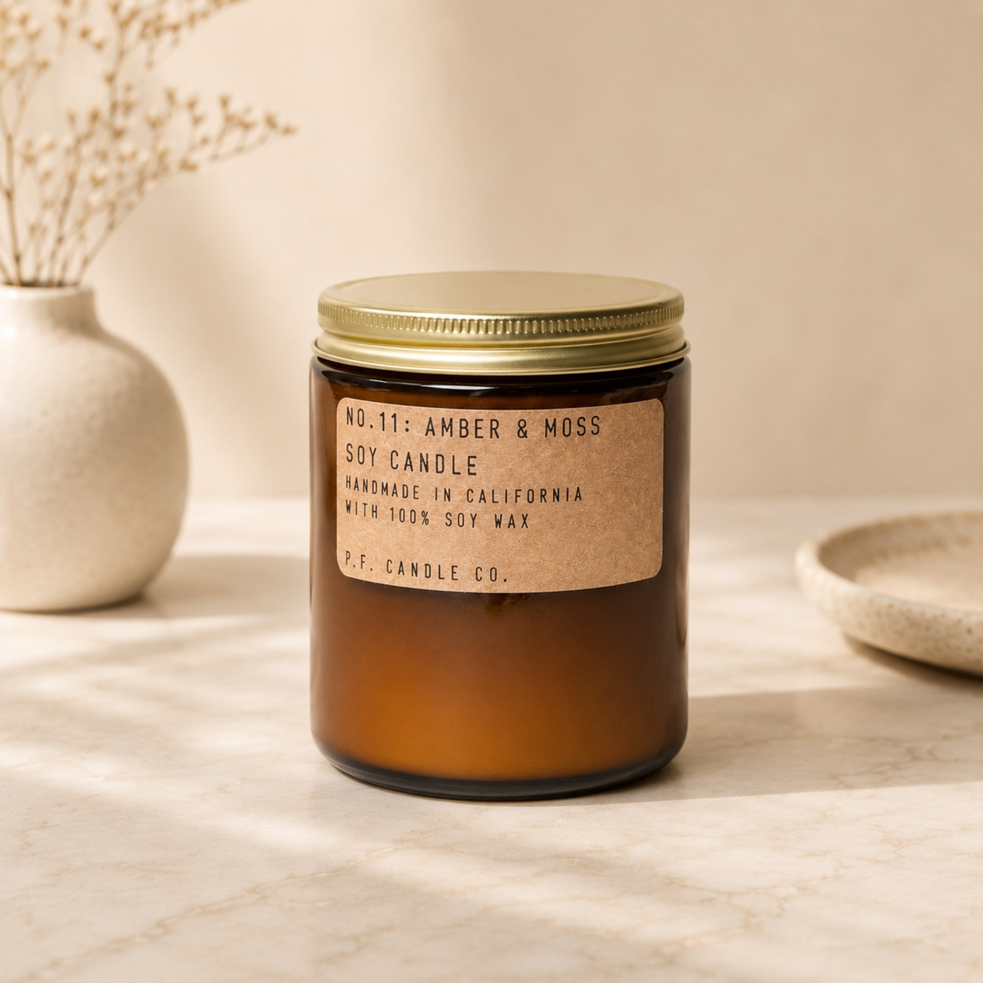Amber soy candle in a glass jar with a gold lid
