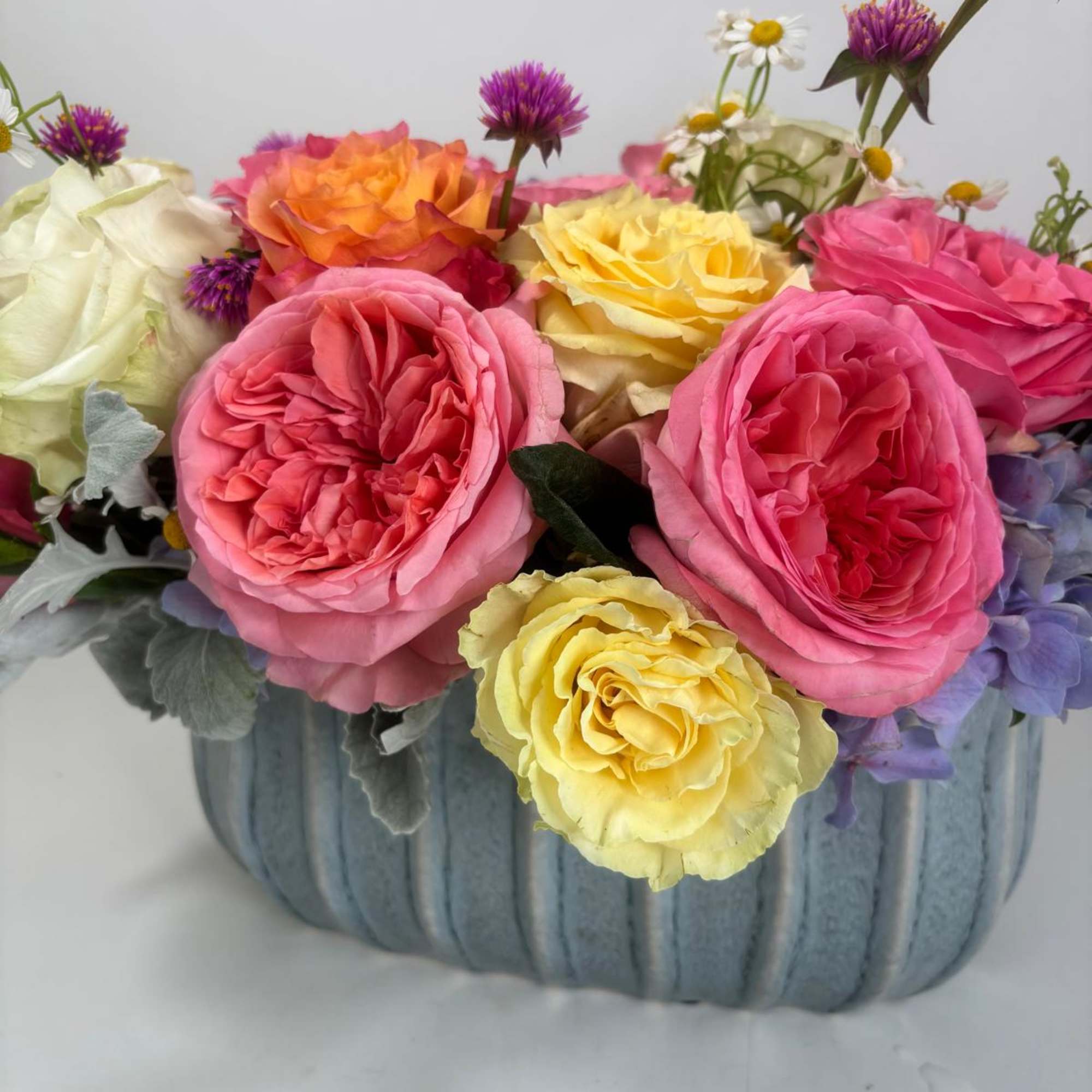 Colorful rose arrangement in a ribbed blue container