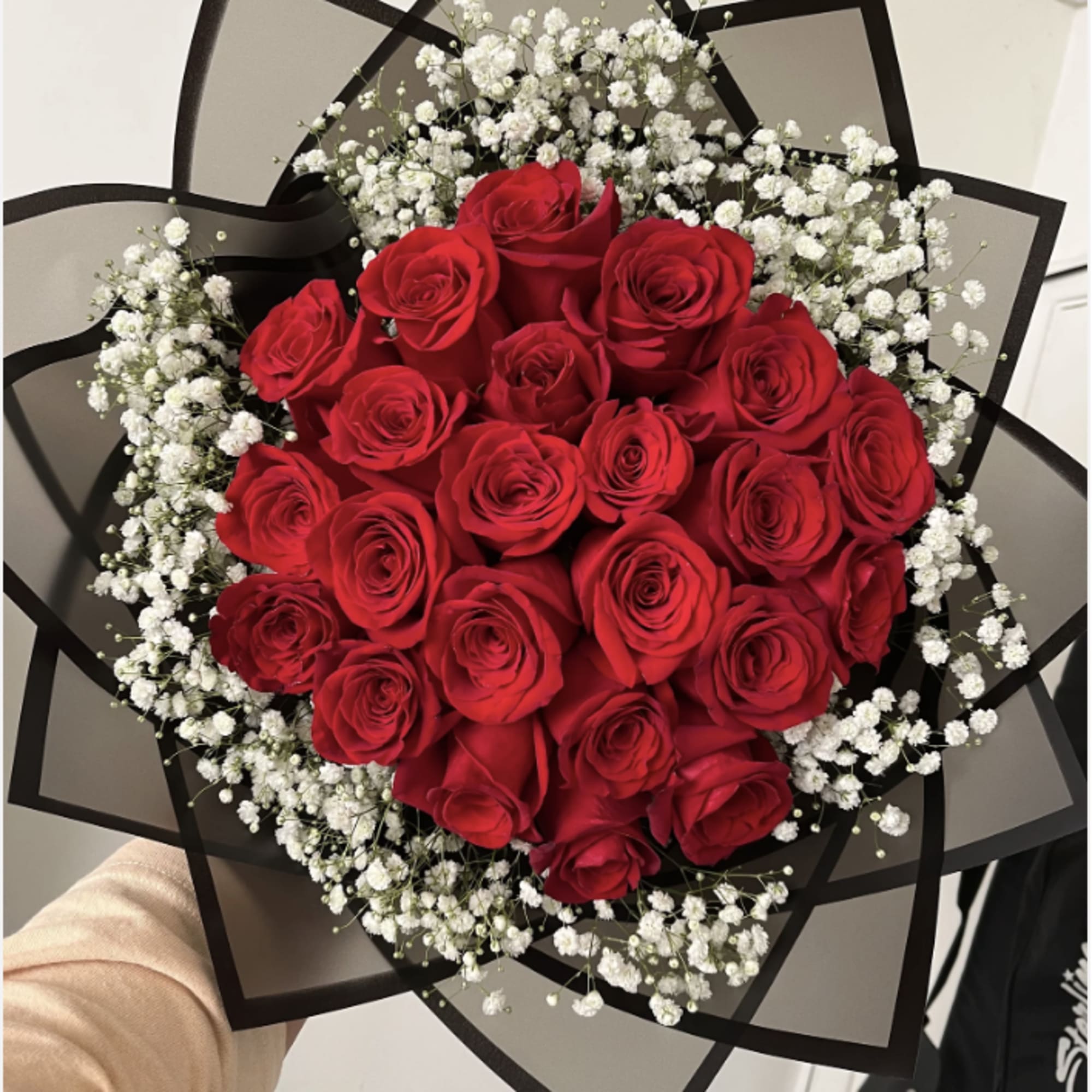 Bouquet of red roses with white baby's breath in black wrap