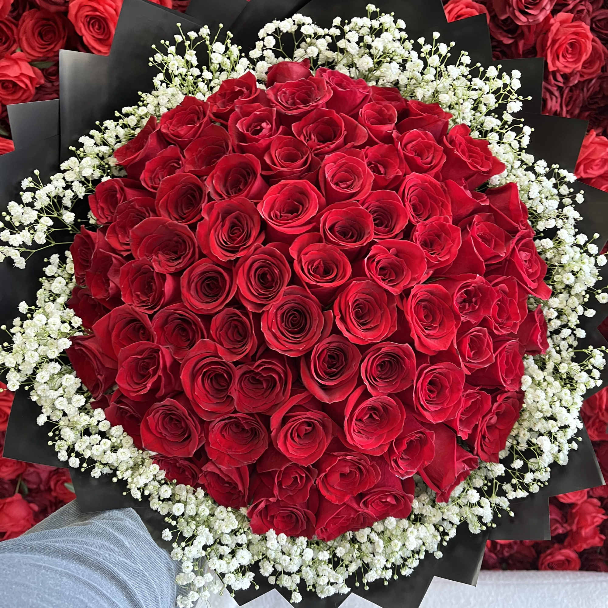 Large bouquet of red roses with white baby's breath in black wrapping