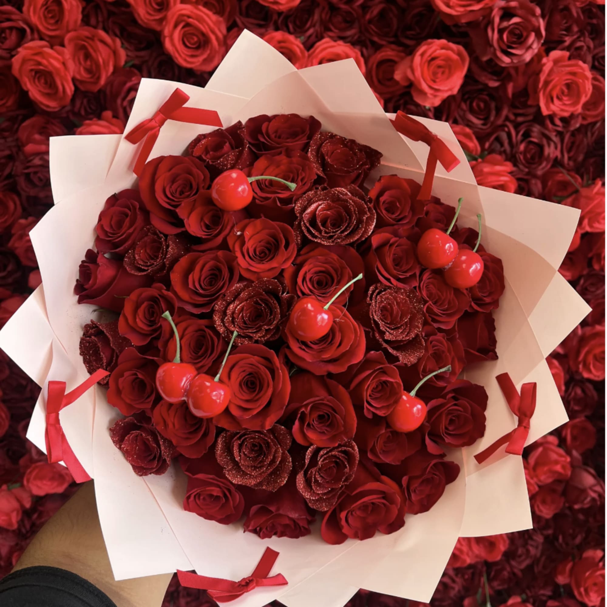Bouquet of red roses with cherry accents in white wrap