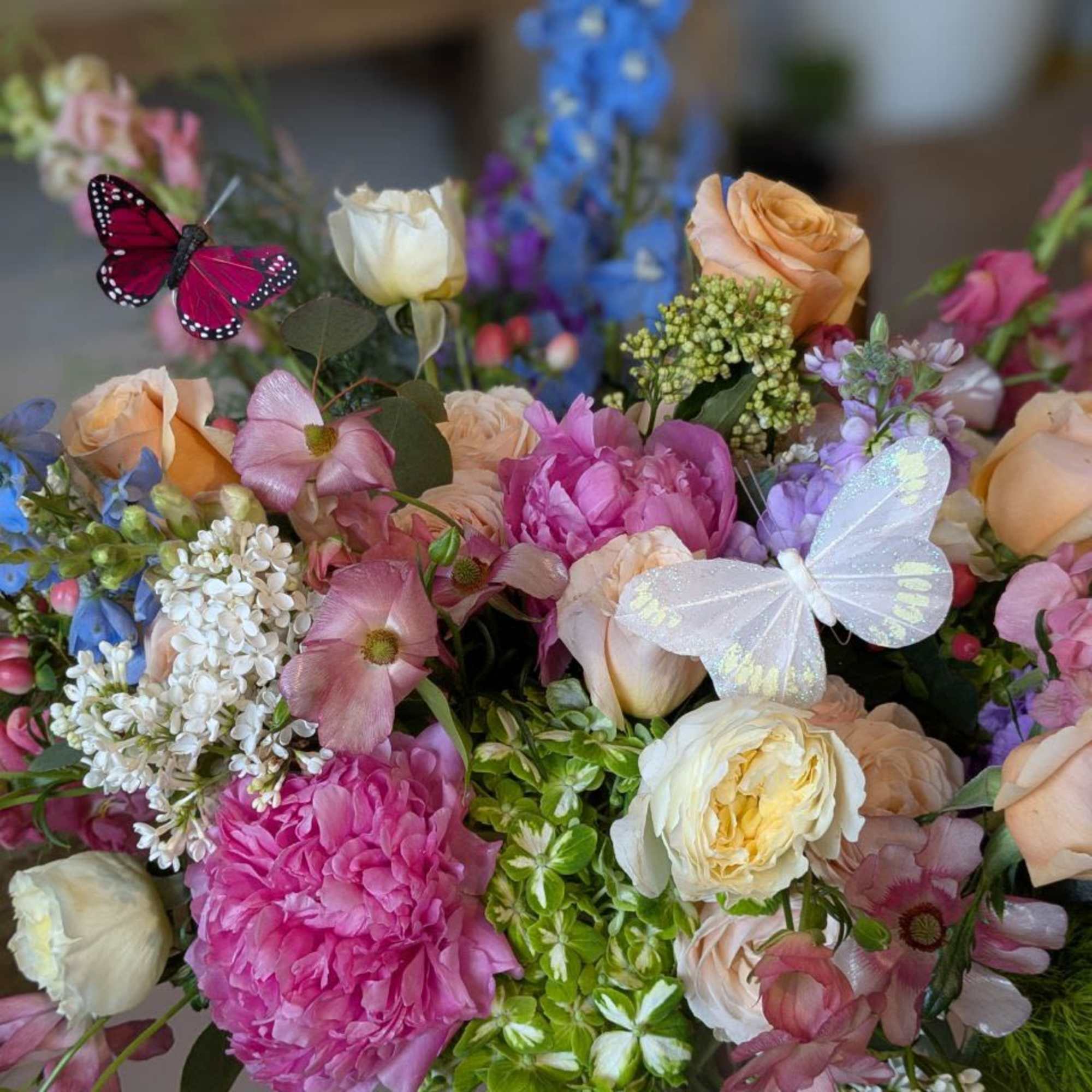 Mixed bouquet of pink, peach, and white flowers with decorative butterflies