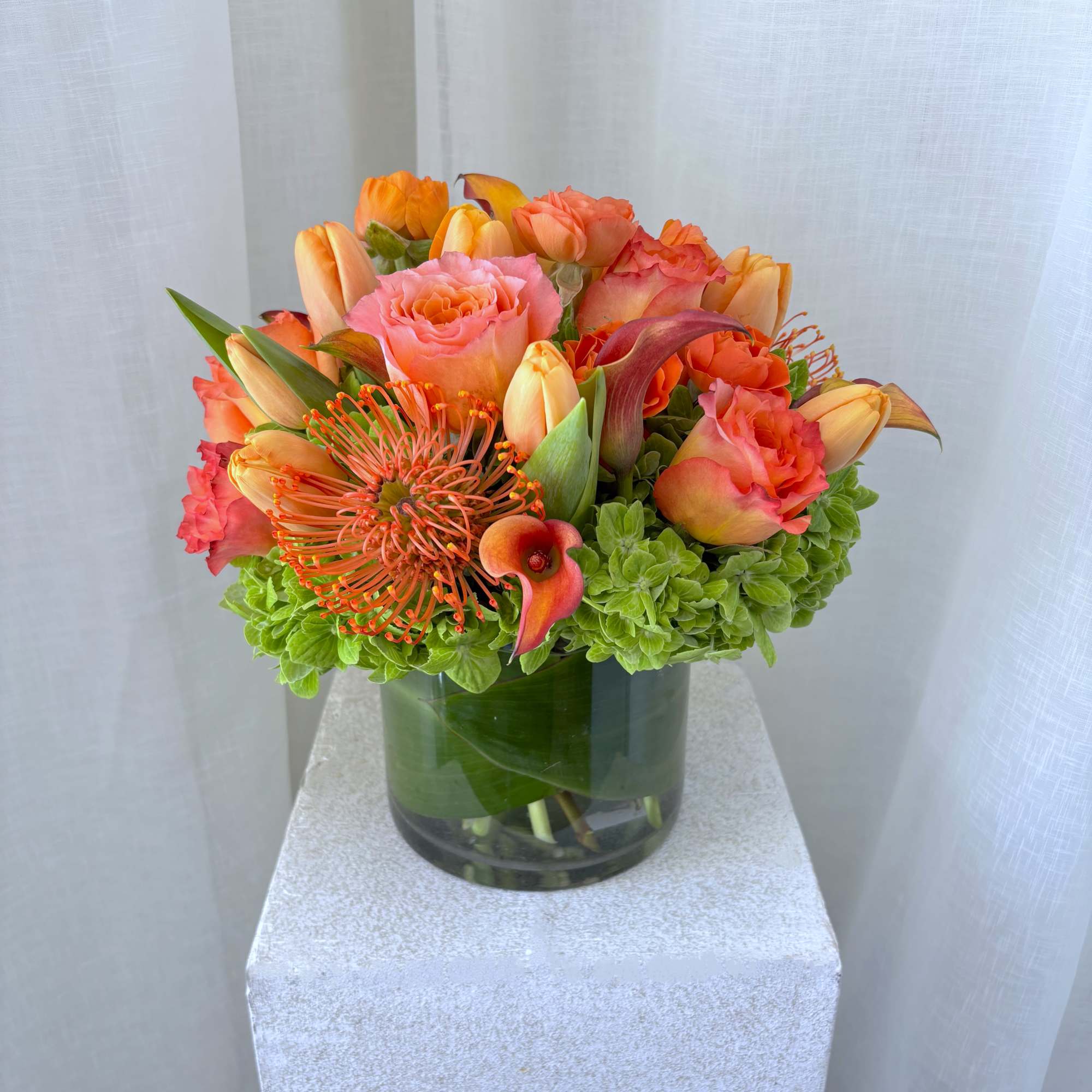 Orange and pink floral arrangement in a glass vase