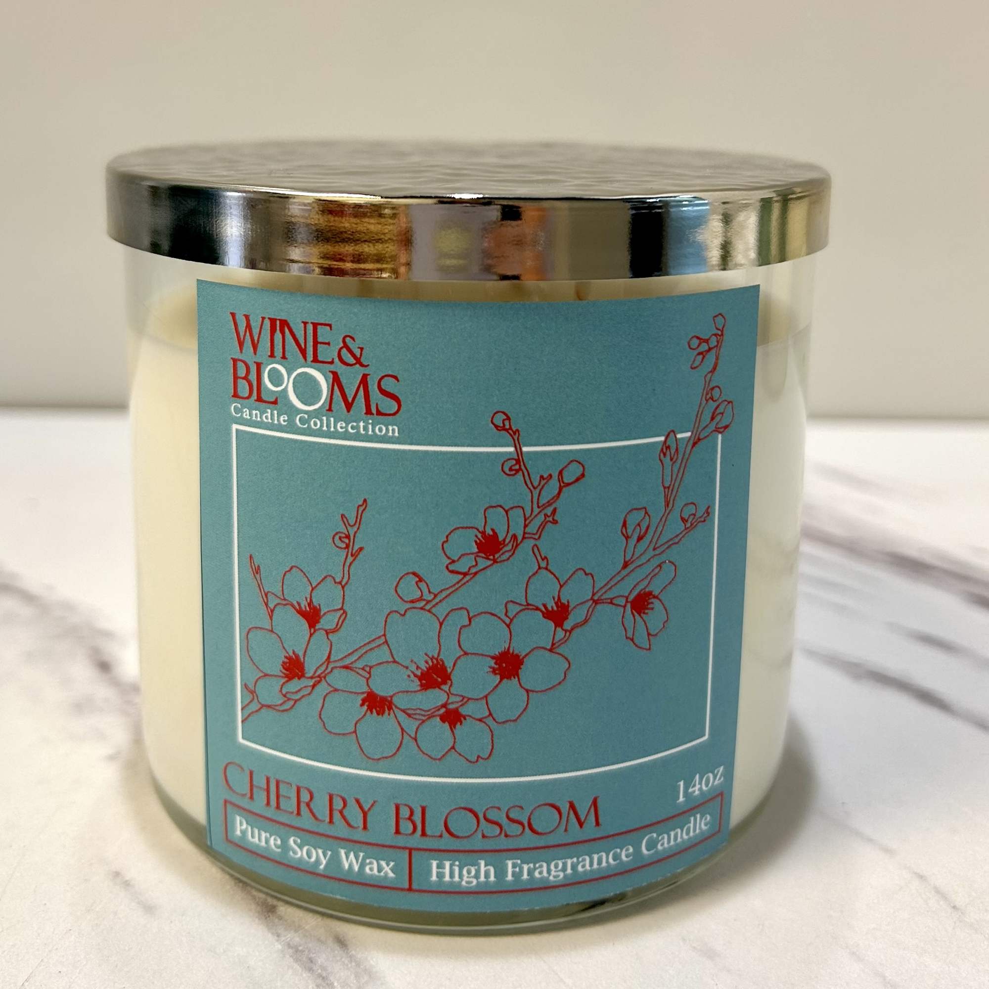 Glass jar candle with a cherry blossom label and metal lid